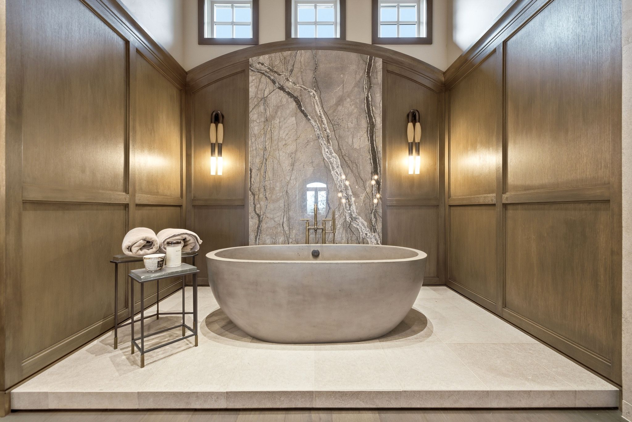 Freestanding oval soaking tub set against a dramatic veined stone feature wall