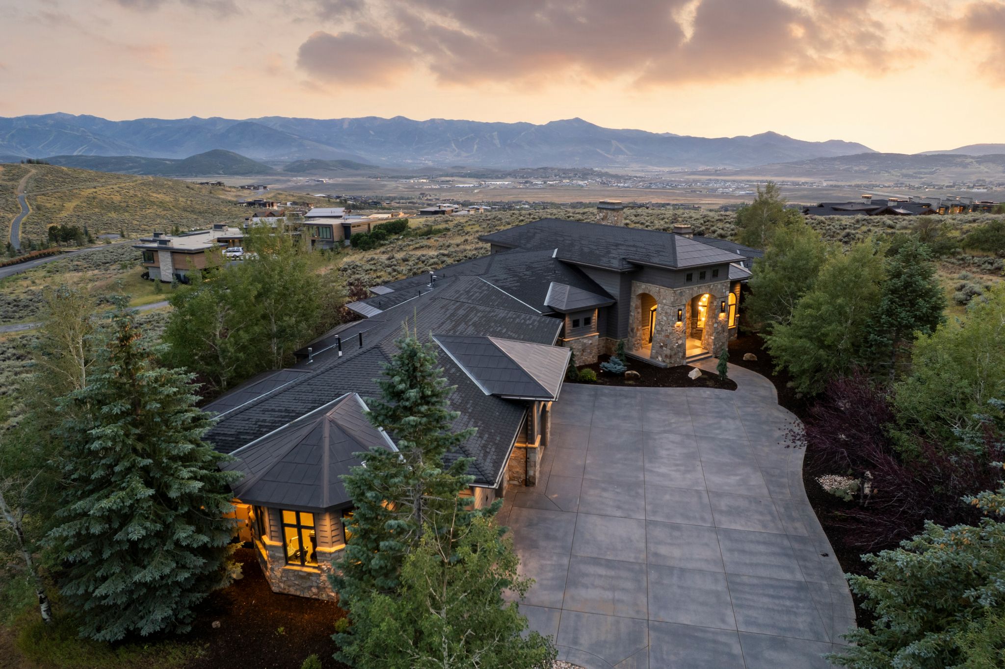 Expansive multi-level residence featuring a stone and stucco exterior, dark shingle roofing, and multiple gables