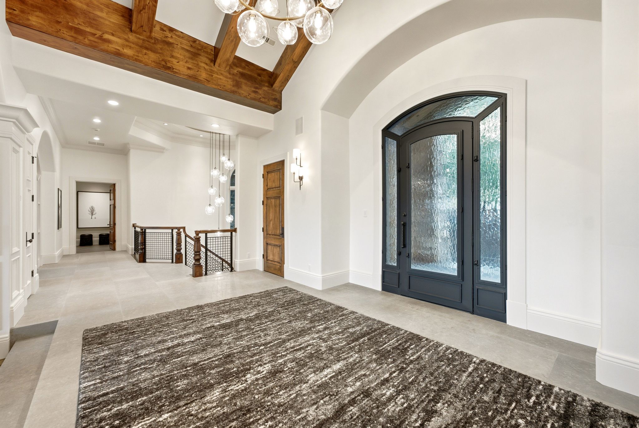 Grand entryway featuring an arched iron and textured glass door
