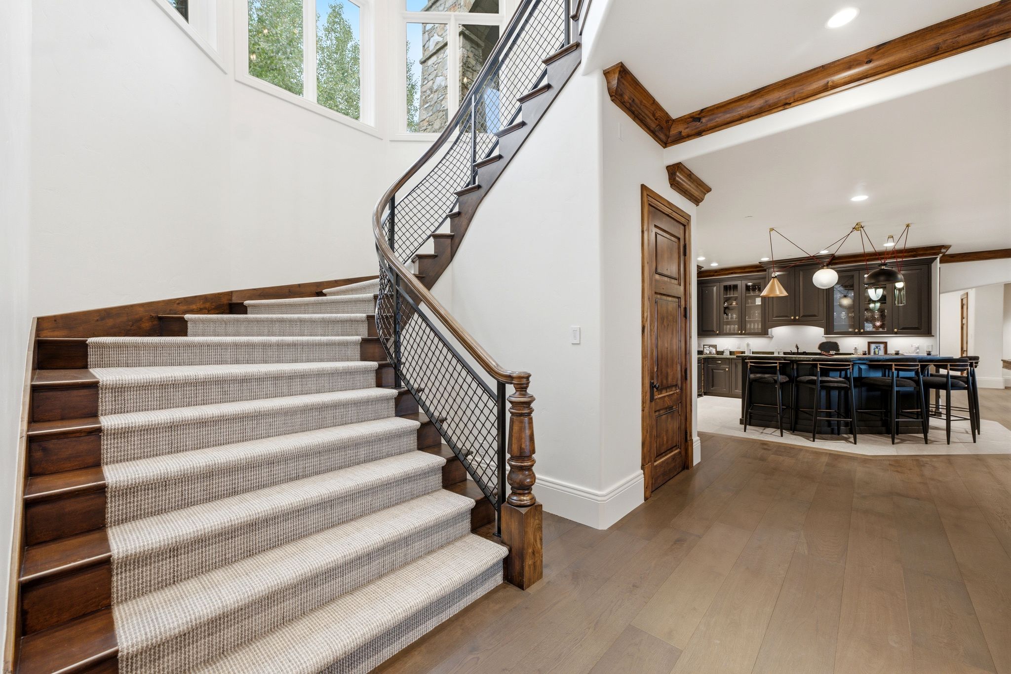 Curved staircase with wood-finish treads and a neutral-toned runner, featuring an industrial-style metal and wood railing