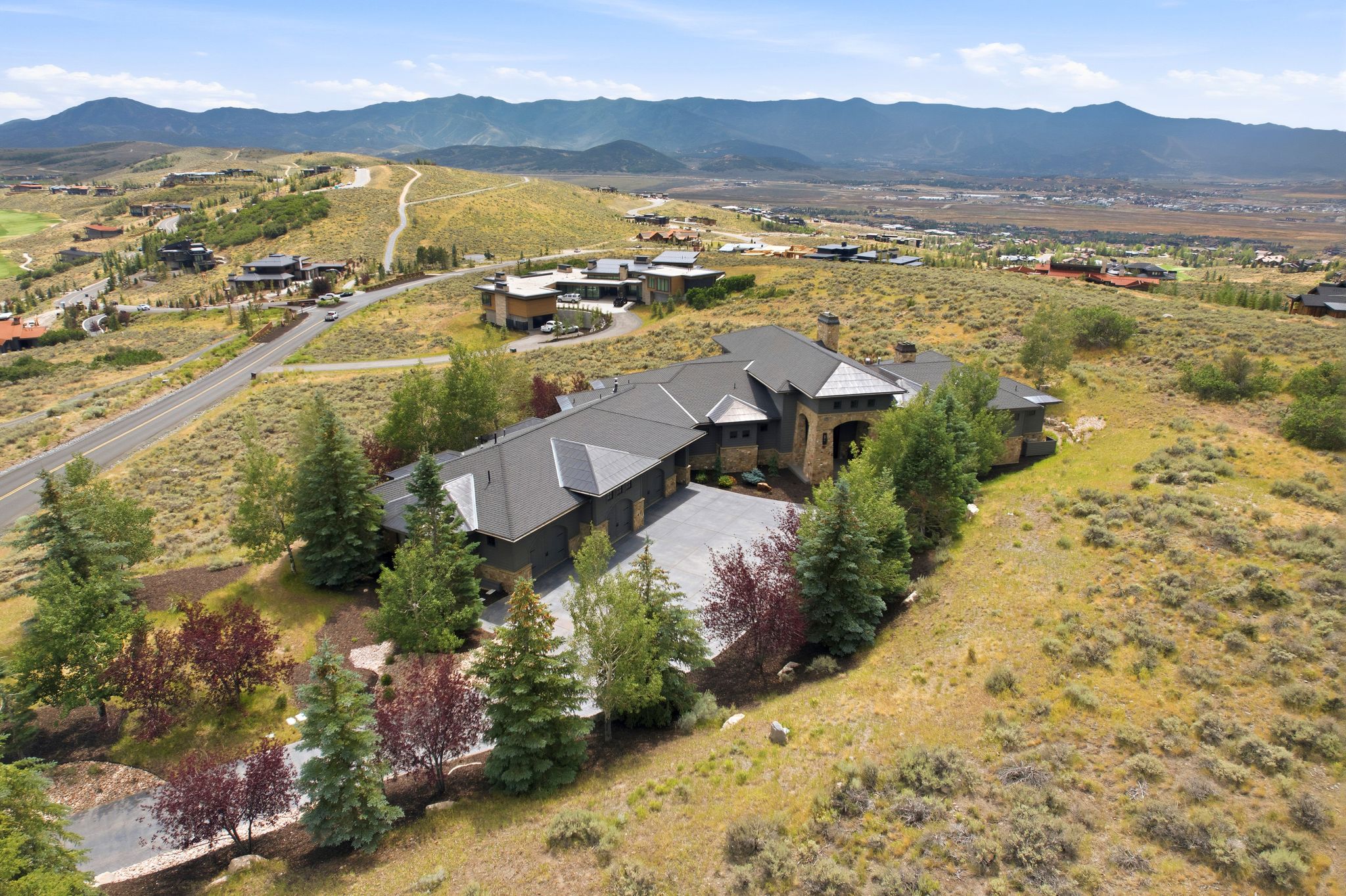 Expansive property featuring a stone and dark siding exterior, a multi-gabled roofline, and an attached three-car garage