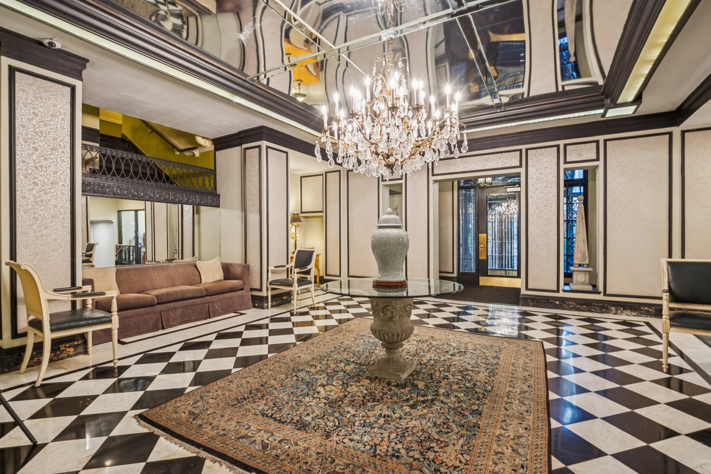 Grand entry foyer featuring a large crystal chandelier, reflective ceiling, and a black and white checkerboard floor