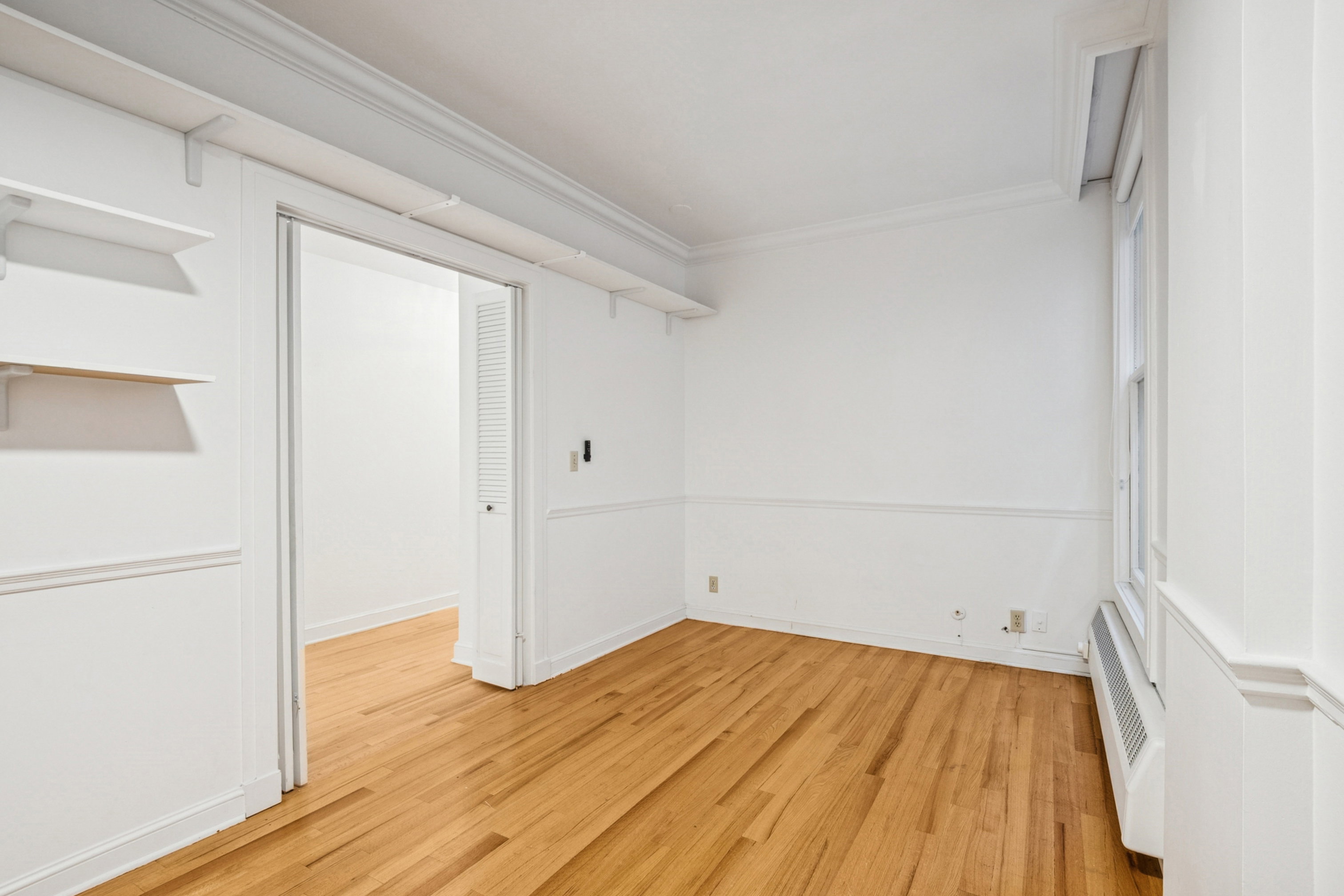Bedroom 1 featuring hardwood flooring, white walls