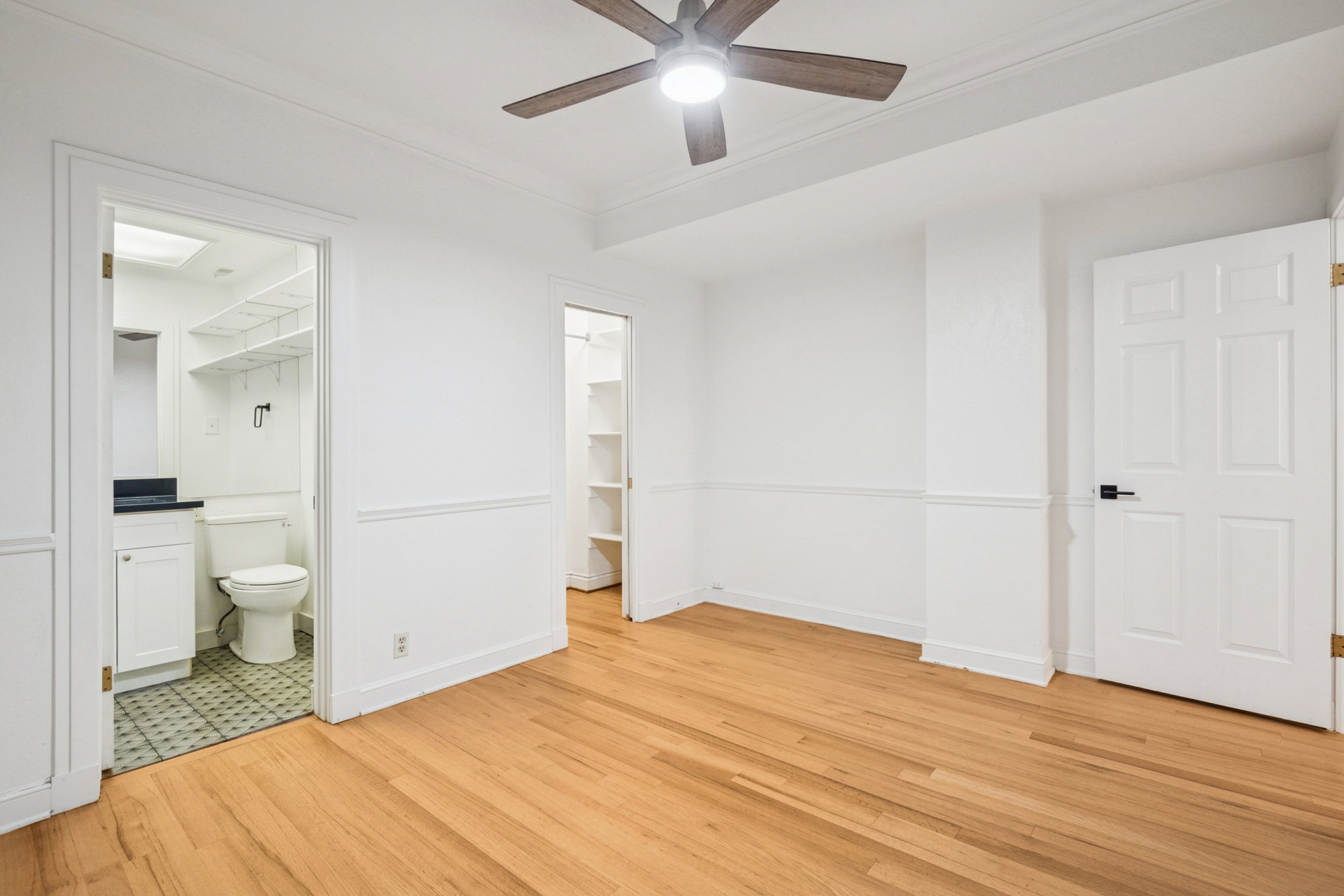 Bedroom 2 featuring hardwood flooring, white walls, and bathroom