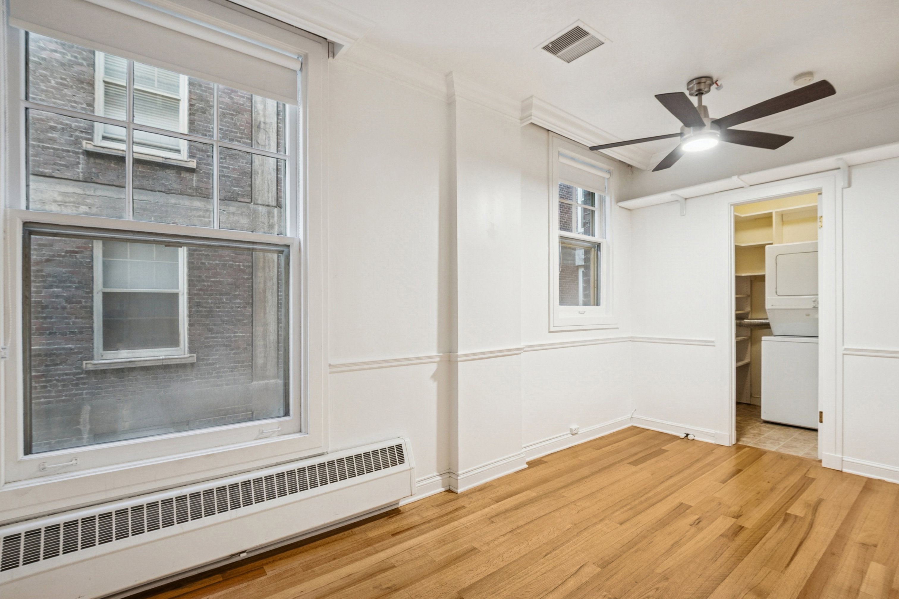 Bedroom 1 featuring hardwood flooring, white walls, and a ceiling fan