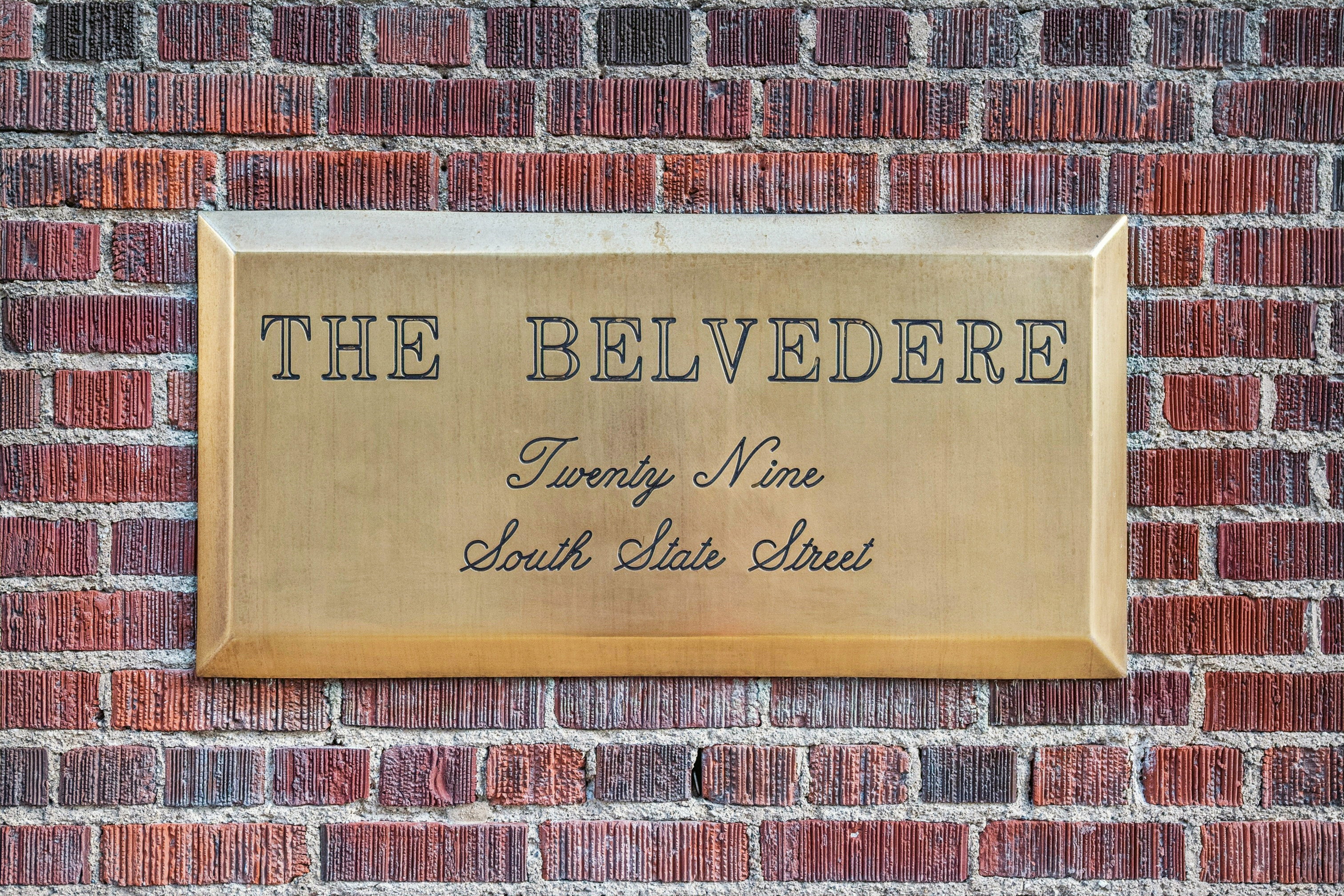 Solid brass plaque with engraved lettering affixed to a textured brick wall
