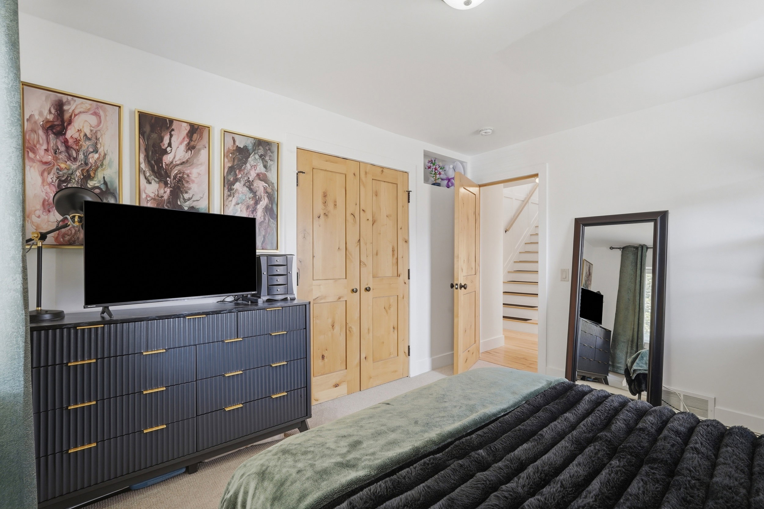 Bedroom featuring light natural wood doors, white walls, and a ceiling light fixture