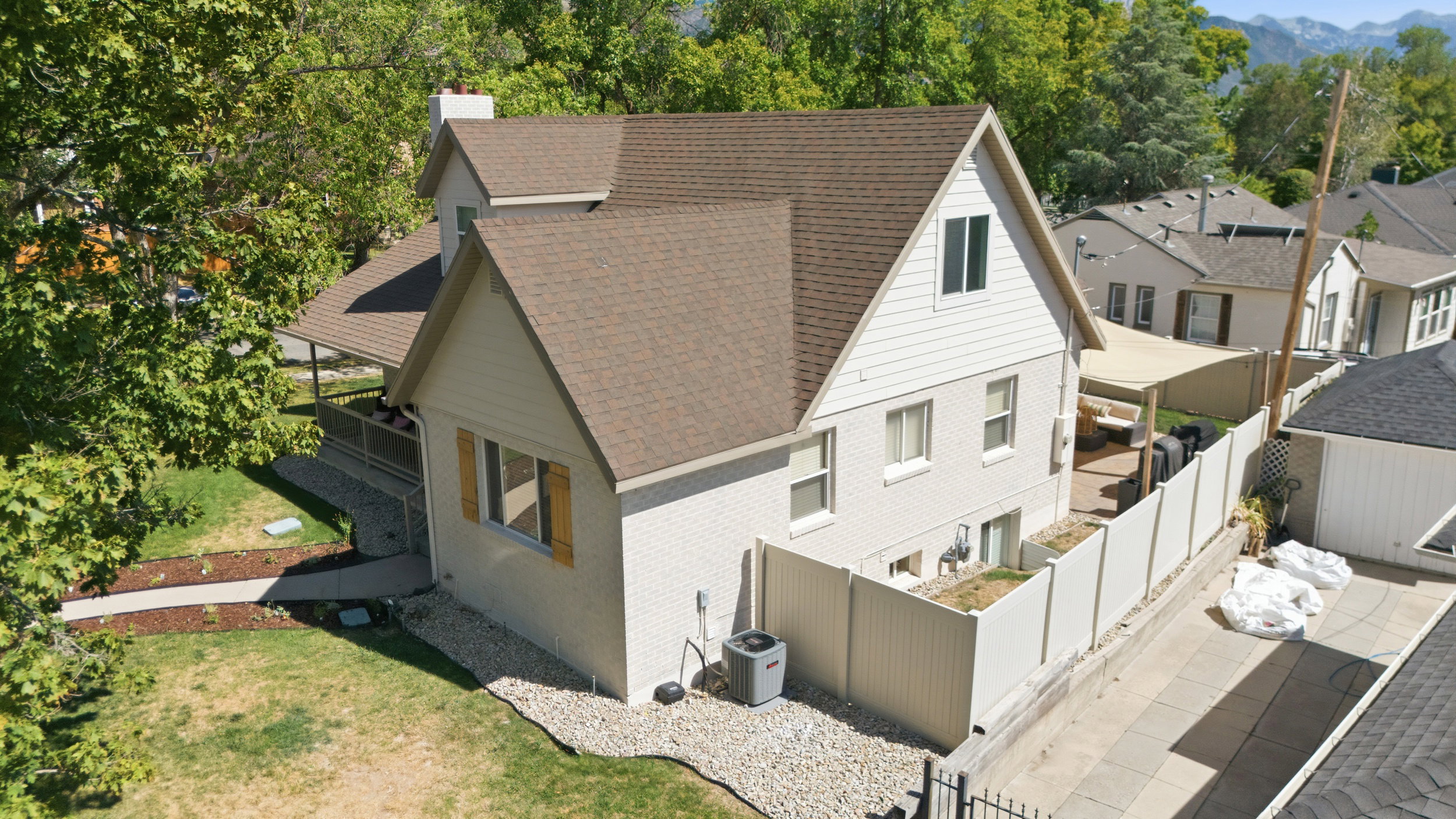 Residential property featuring a light-colored exterior with a brown shingled roof