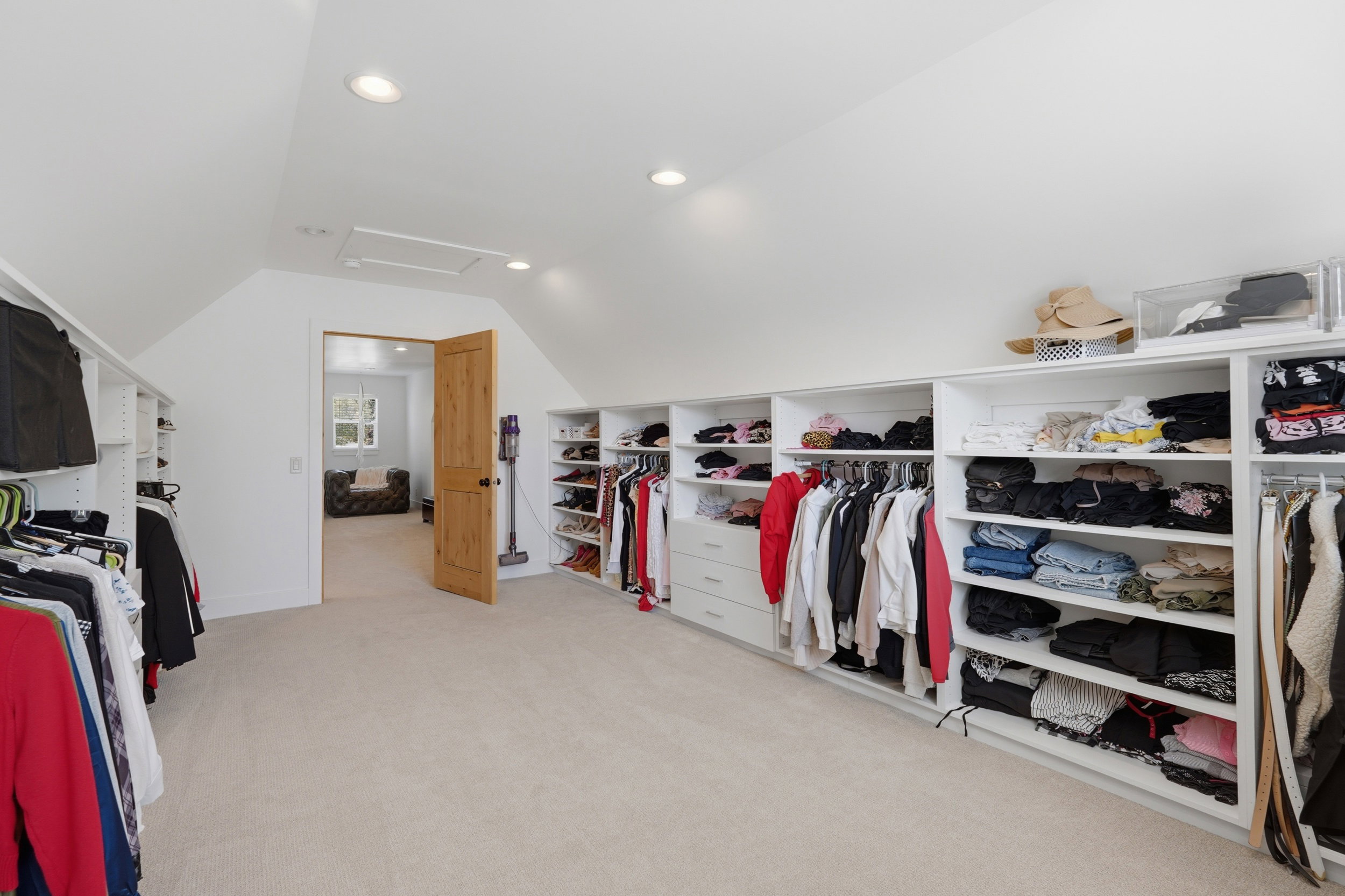 Spacious walk-in closet featuring extensive built-in shelving, hanging rods, and integrated drawer storage