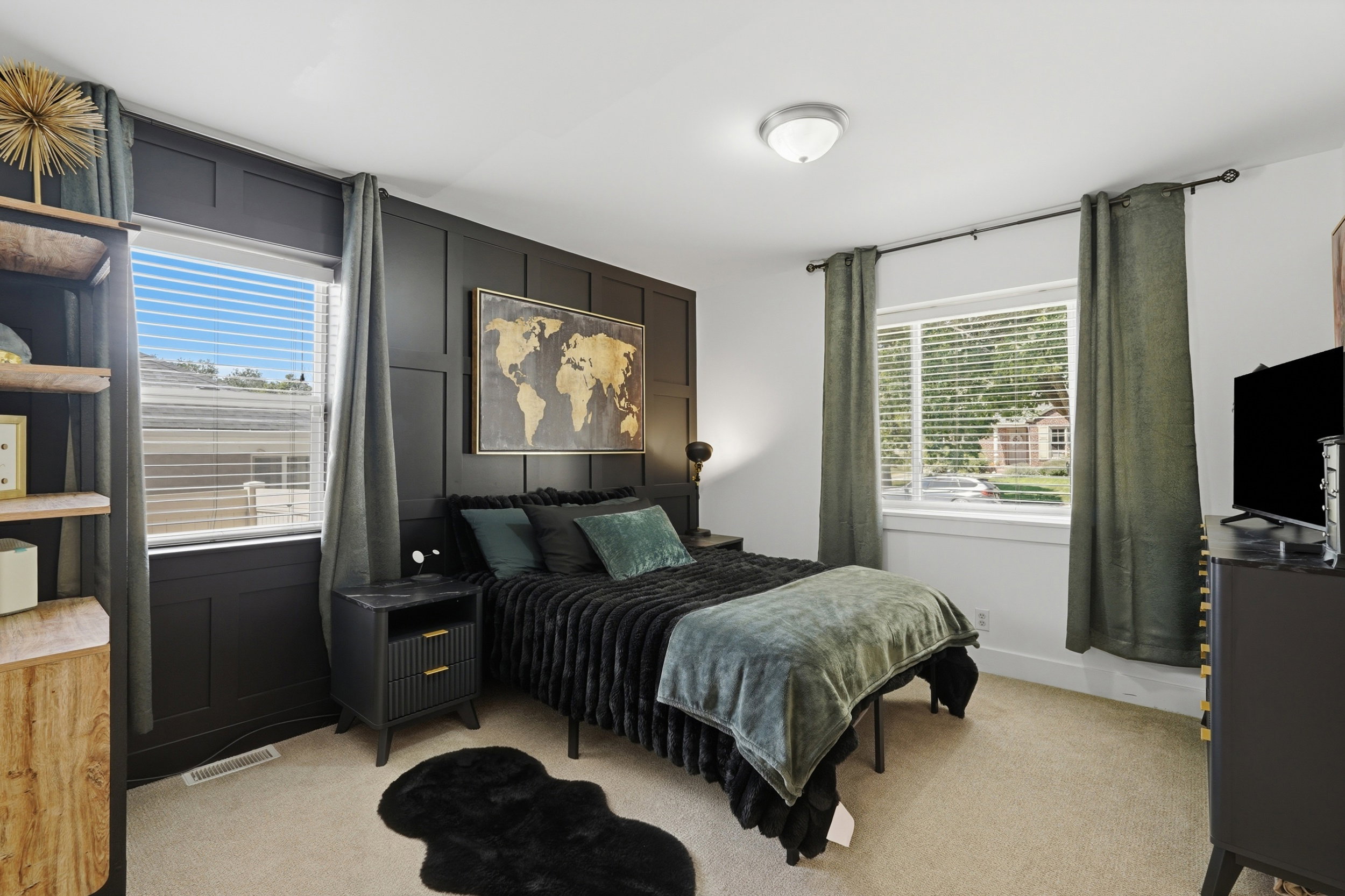 Bedroom featuring a dark accent wall with panel molding, light neutral carpet, two windows with blinds, and an overhead semi-flush mount light fixture