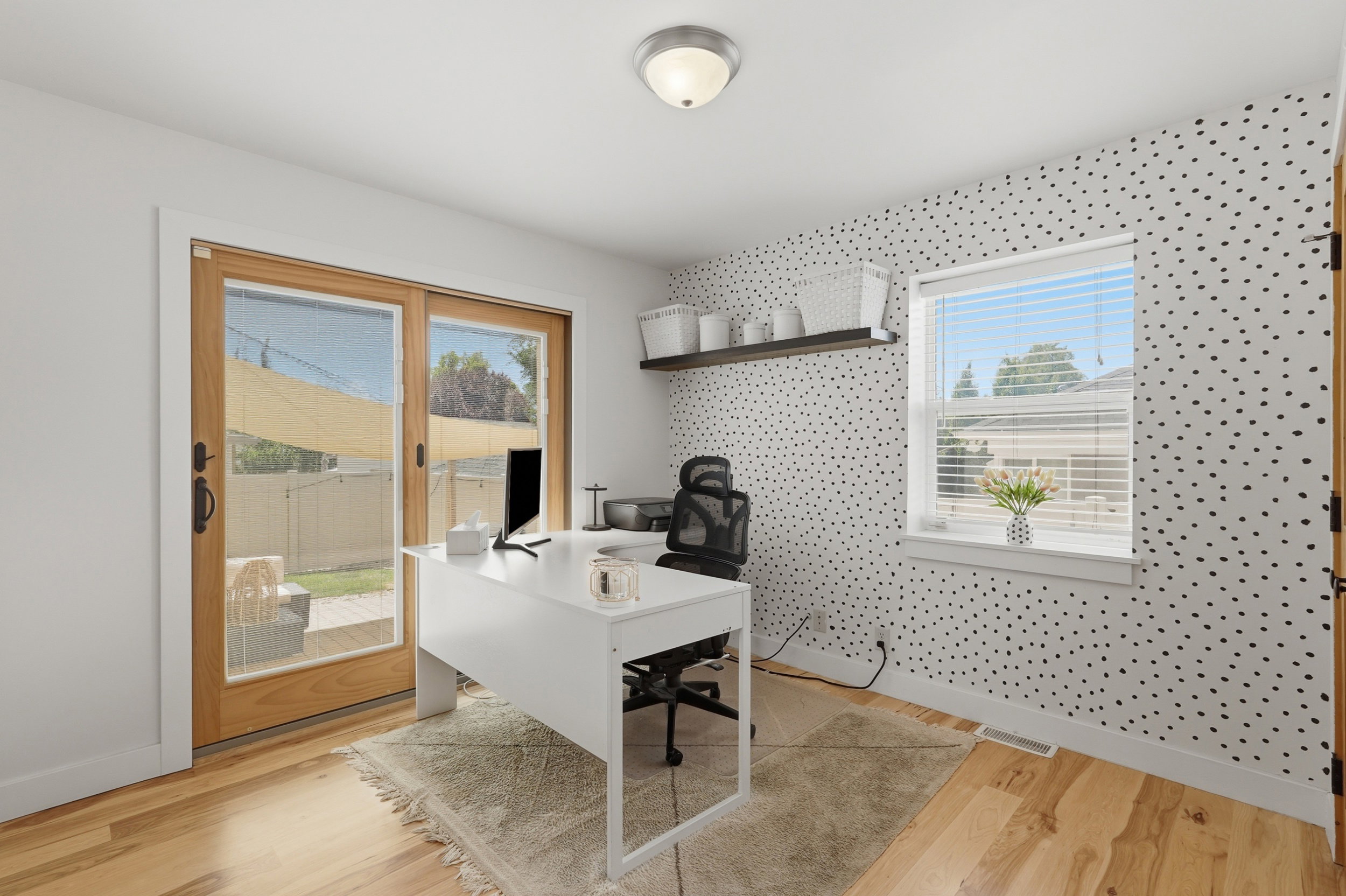 Room featuring light wood-finish flooring, white walls, and an accent wall with a polka-dot pattern