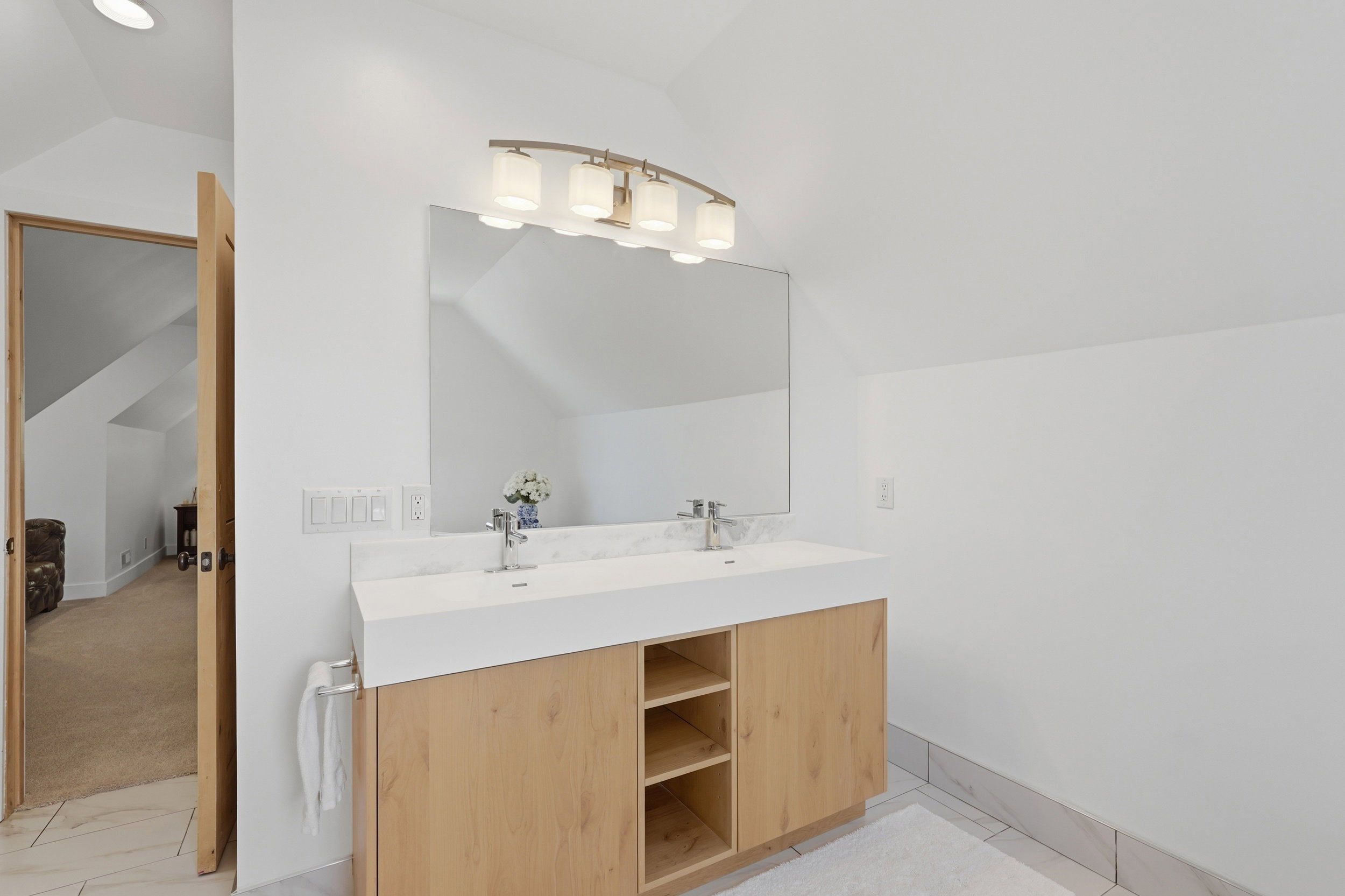Owners ensuite. Dual sink vanity with wood-finish cabinetry, integrated countertop, and brushed nickel fixtures