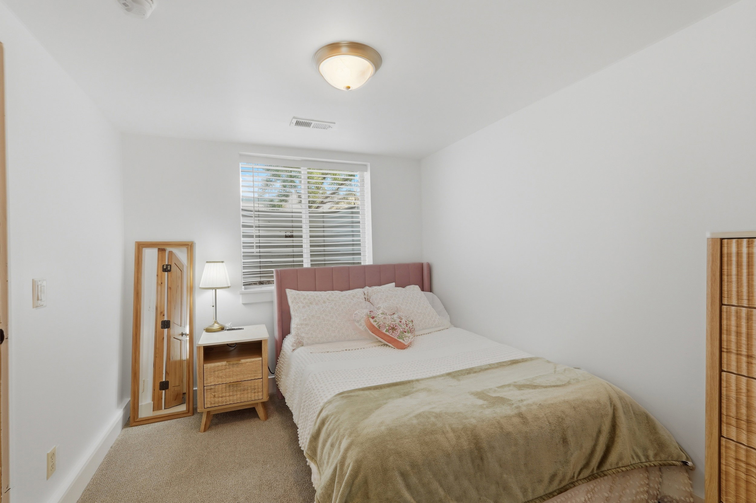 Carpeted room featuring a single window with blinds, white walls, and a ceiling-mounted light fixture
