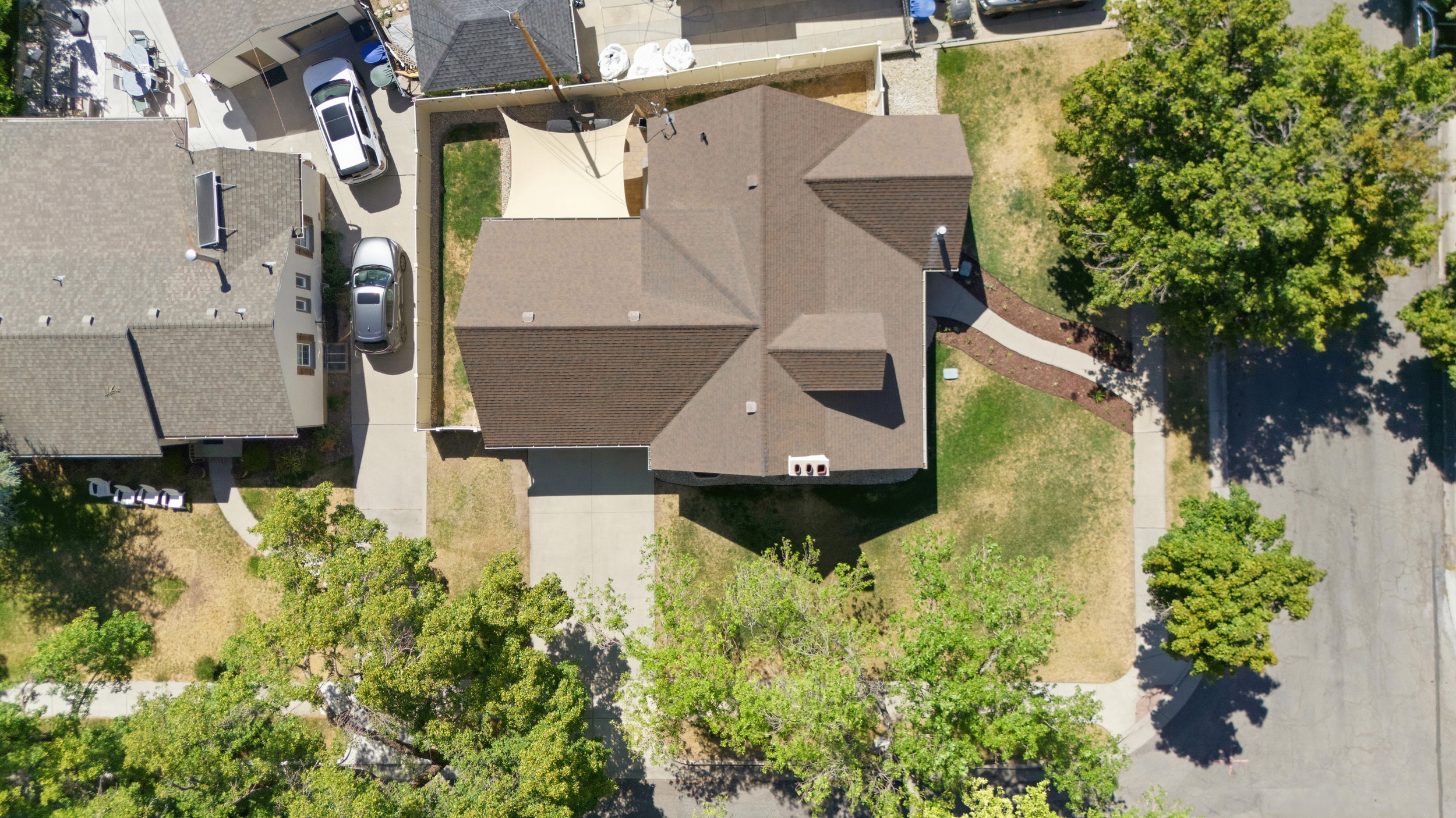 roofline residence featuring architectural shingles, a concrete driveway and an additional paved side driveway