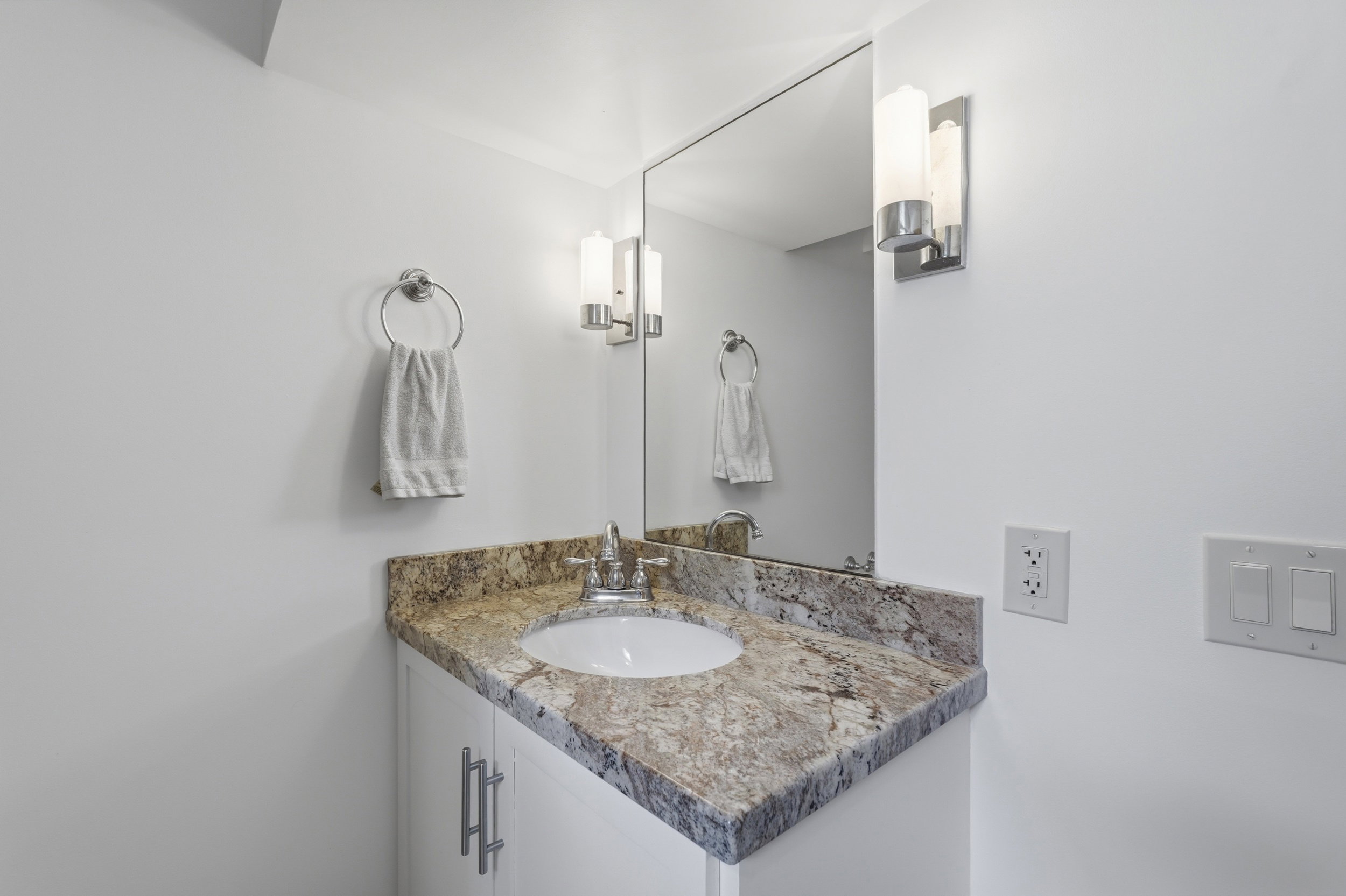 Vanity featuring a polished countertop with natural stone patterning, an undermount sink, and chrome fixtures