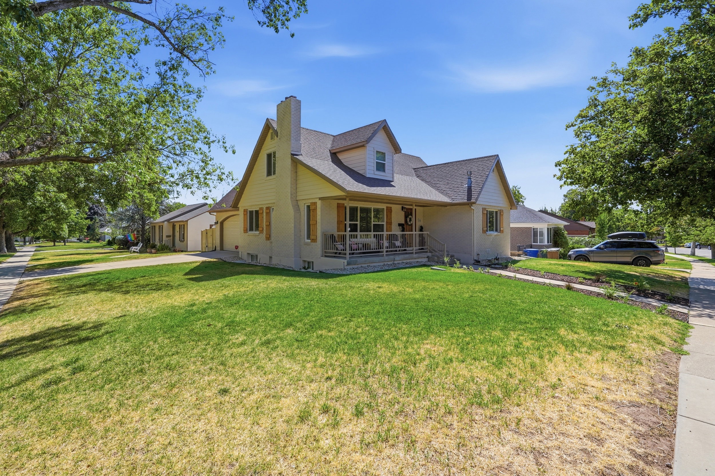 Traditional-style home featuring a covered front porch, dormer window, and a prominent chimney