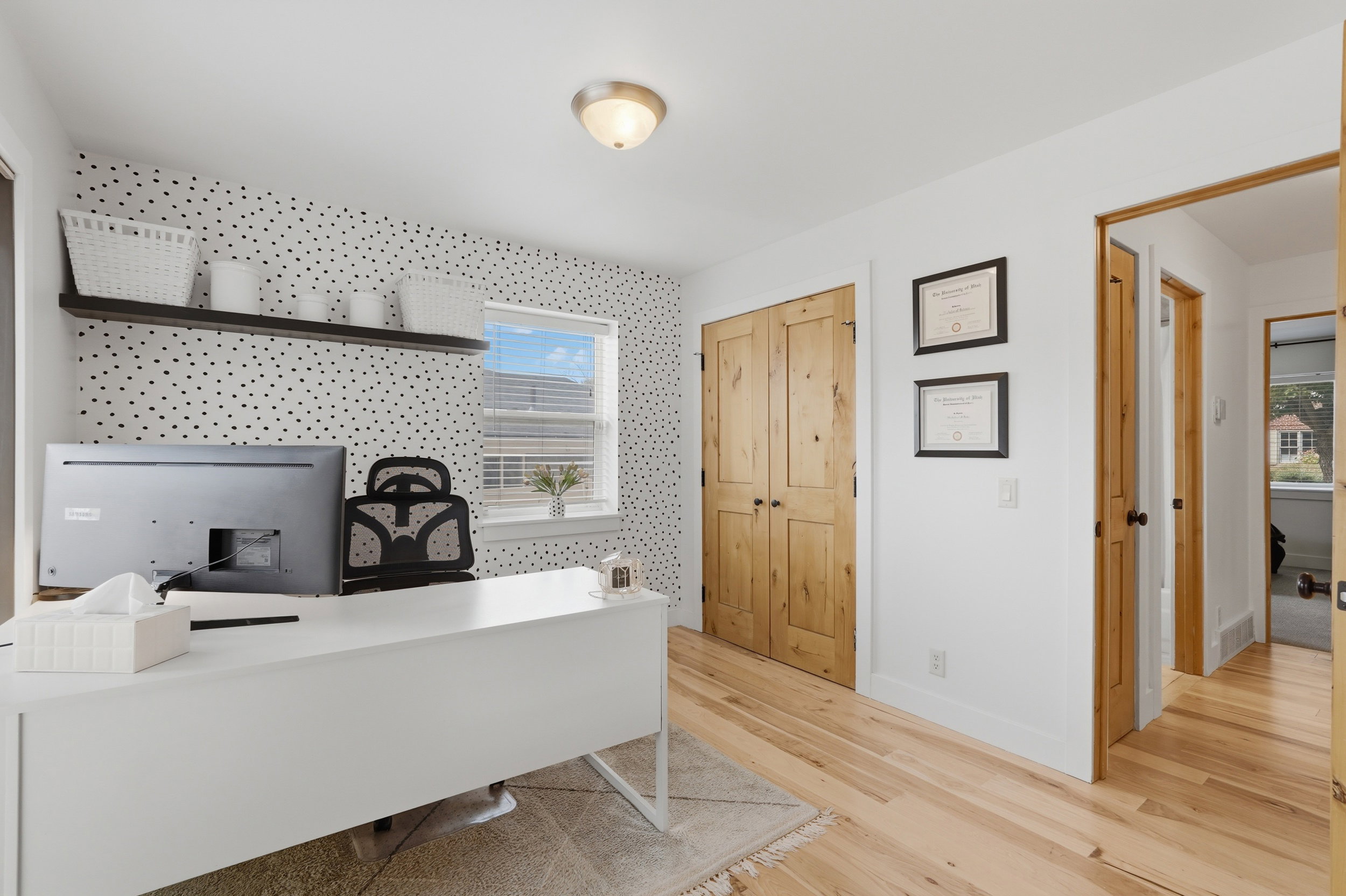 Room featuring wood-finish flooring, a window with horizontal blinds, and a built-in wall shelf