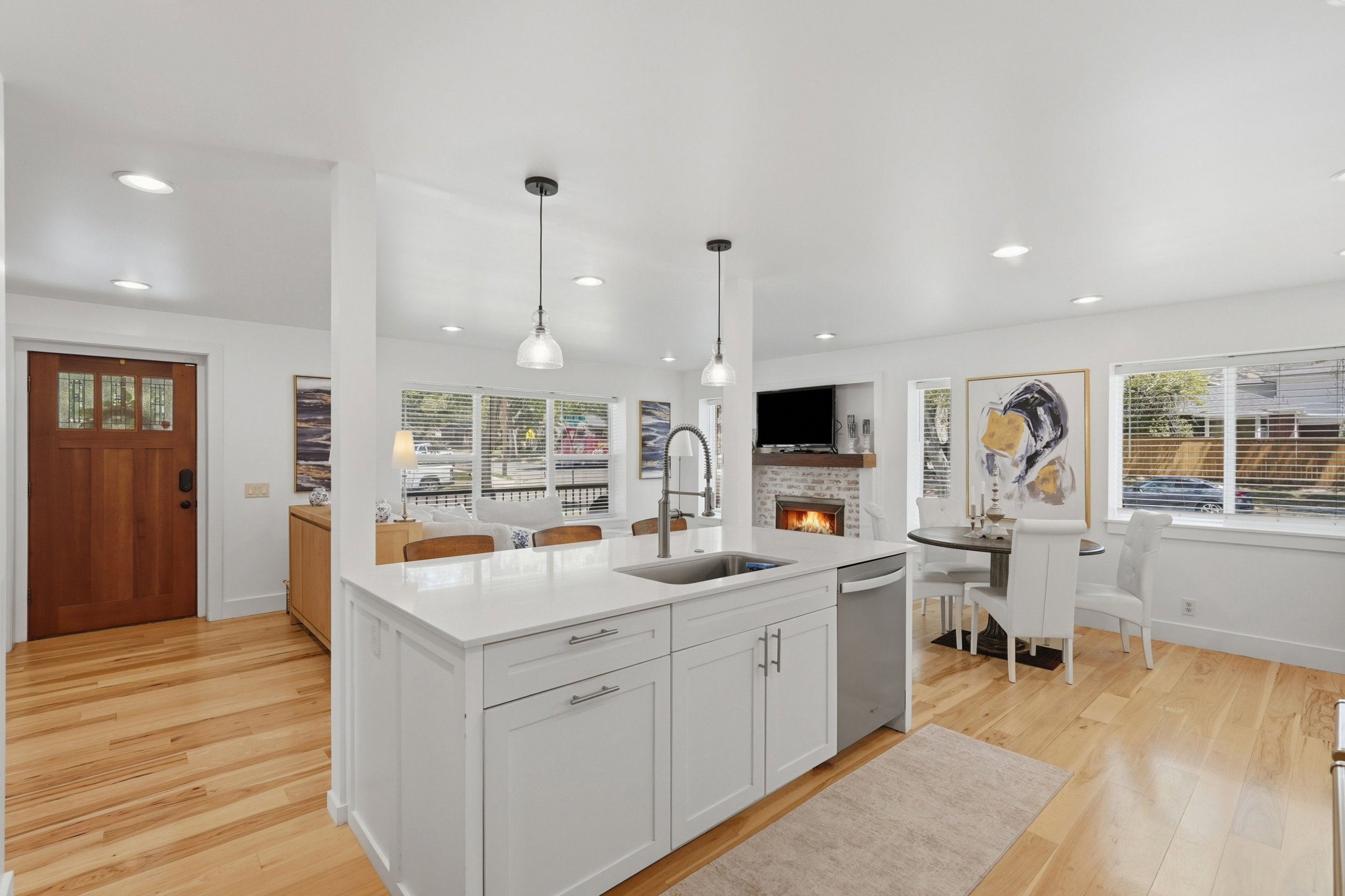 Kitchen island with white cabinetry, a built-in stainless steel sink, and pendant lighting