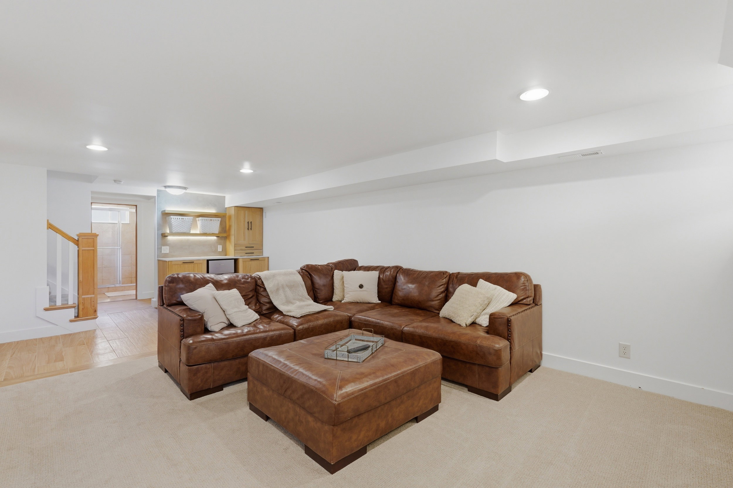 Spacious recreation room featuring recessed lighting, a built-in wet bar with wood cabinetry, and neutral carpeting