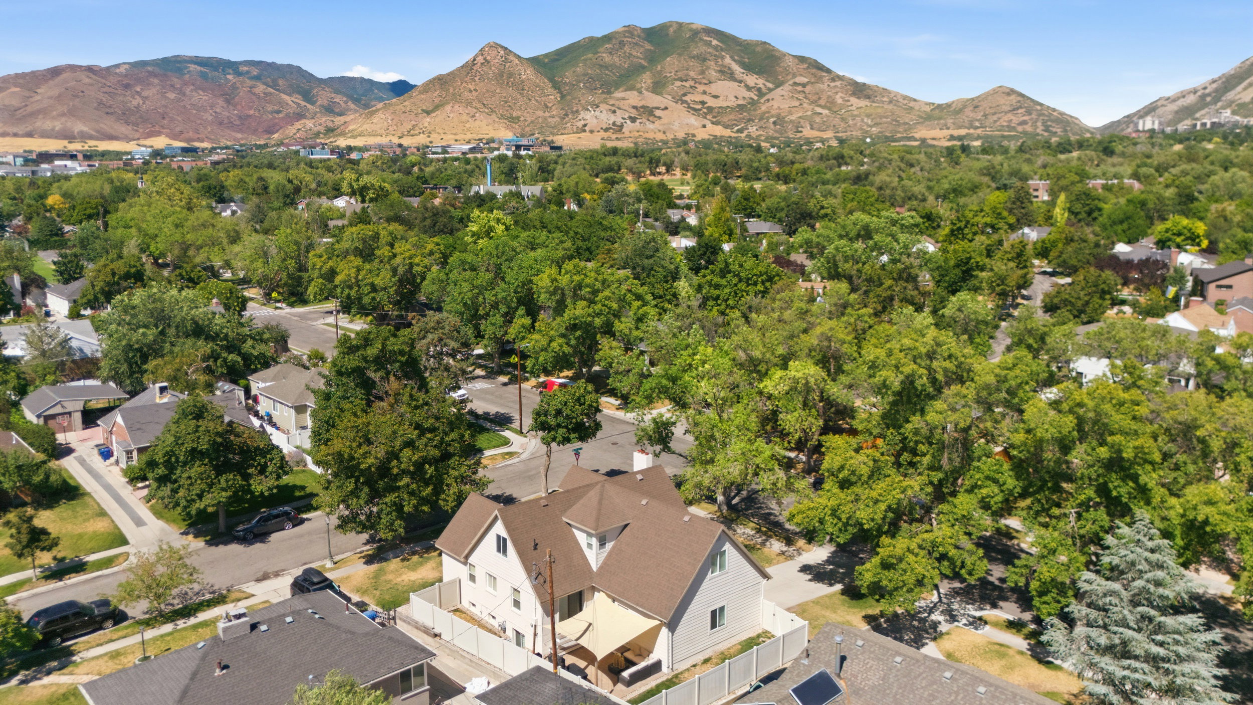 Residential property featuring a light-colored exterior and brown shingle roofing