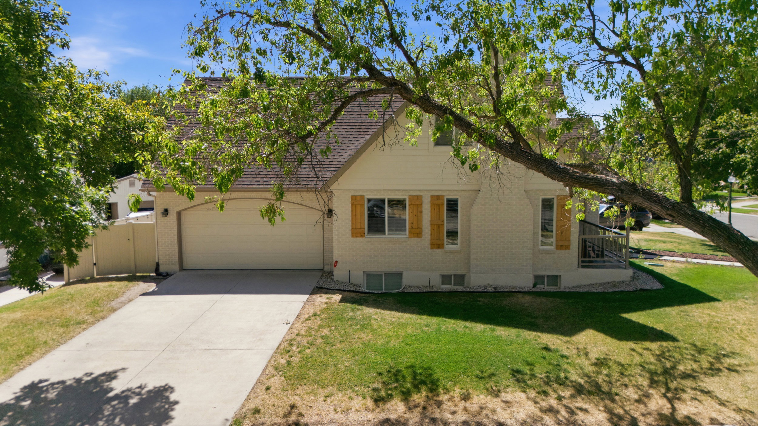 Two Story residence featuring a two-car garage with an arched opening, a paved driveway, and a front yard with mature trees