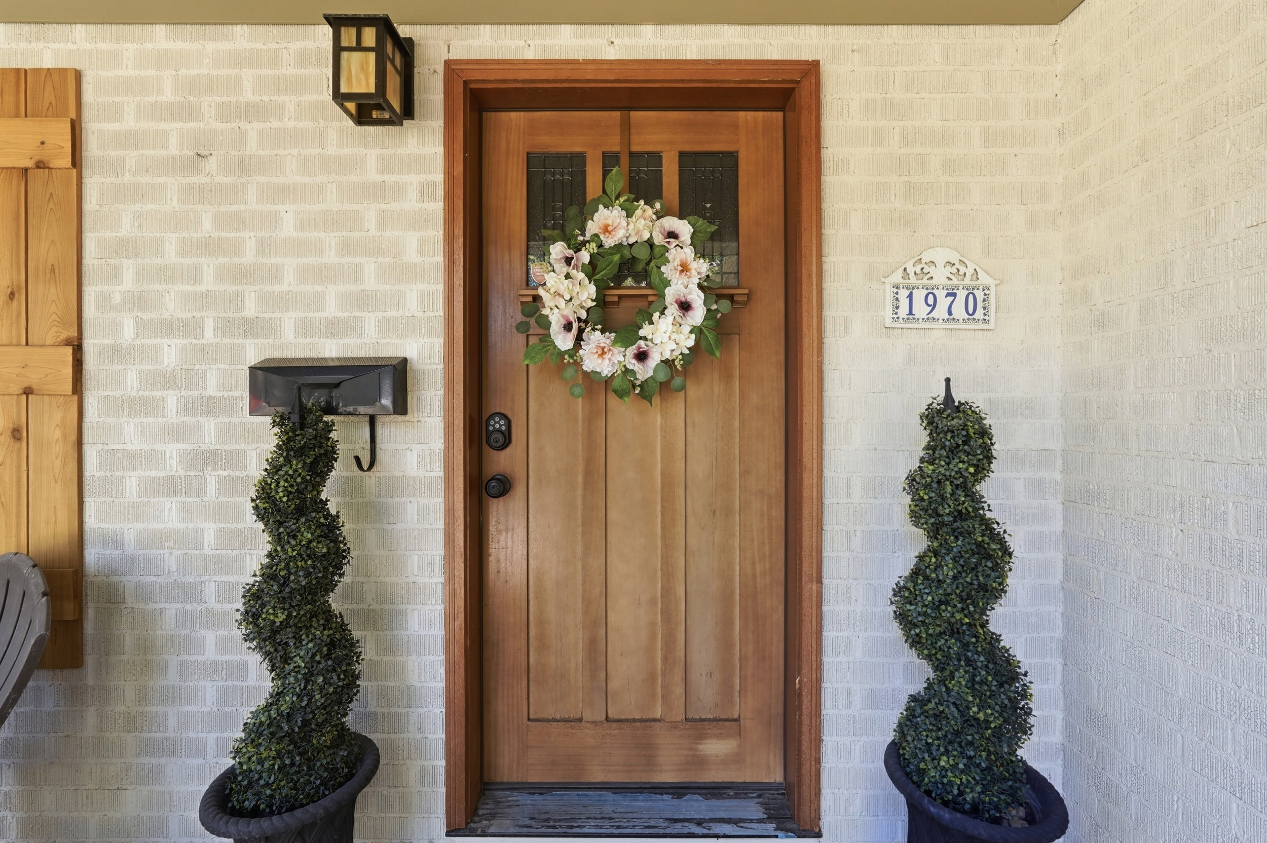 Entryway featuring a wood door with glass inserts, light brick facade, and a wall-mounted light fixture