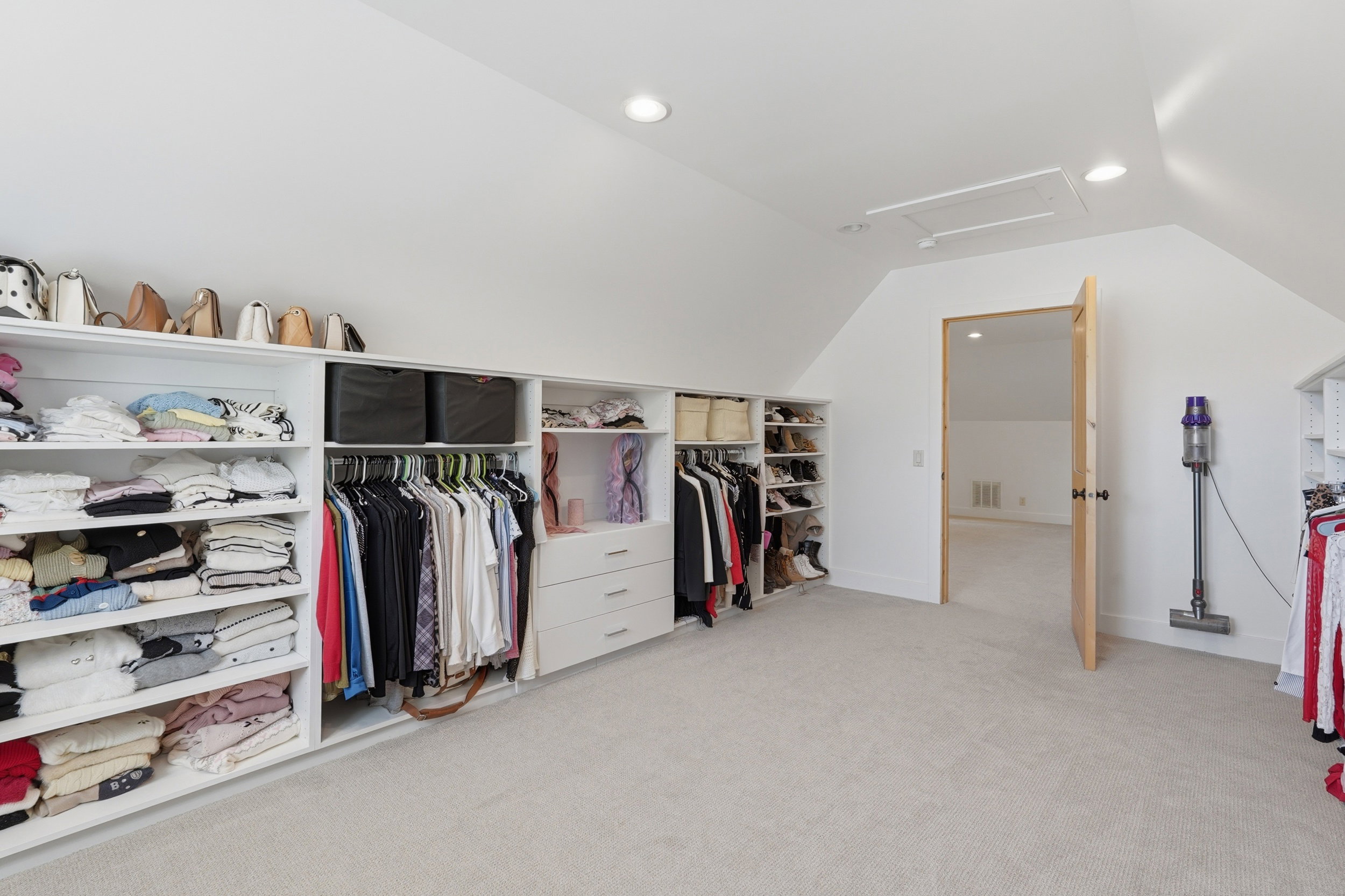 Carpeted room with a vaulted ceiling and recessed lighting, featuring extensive built-in storage