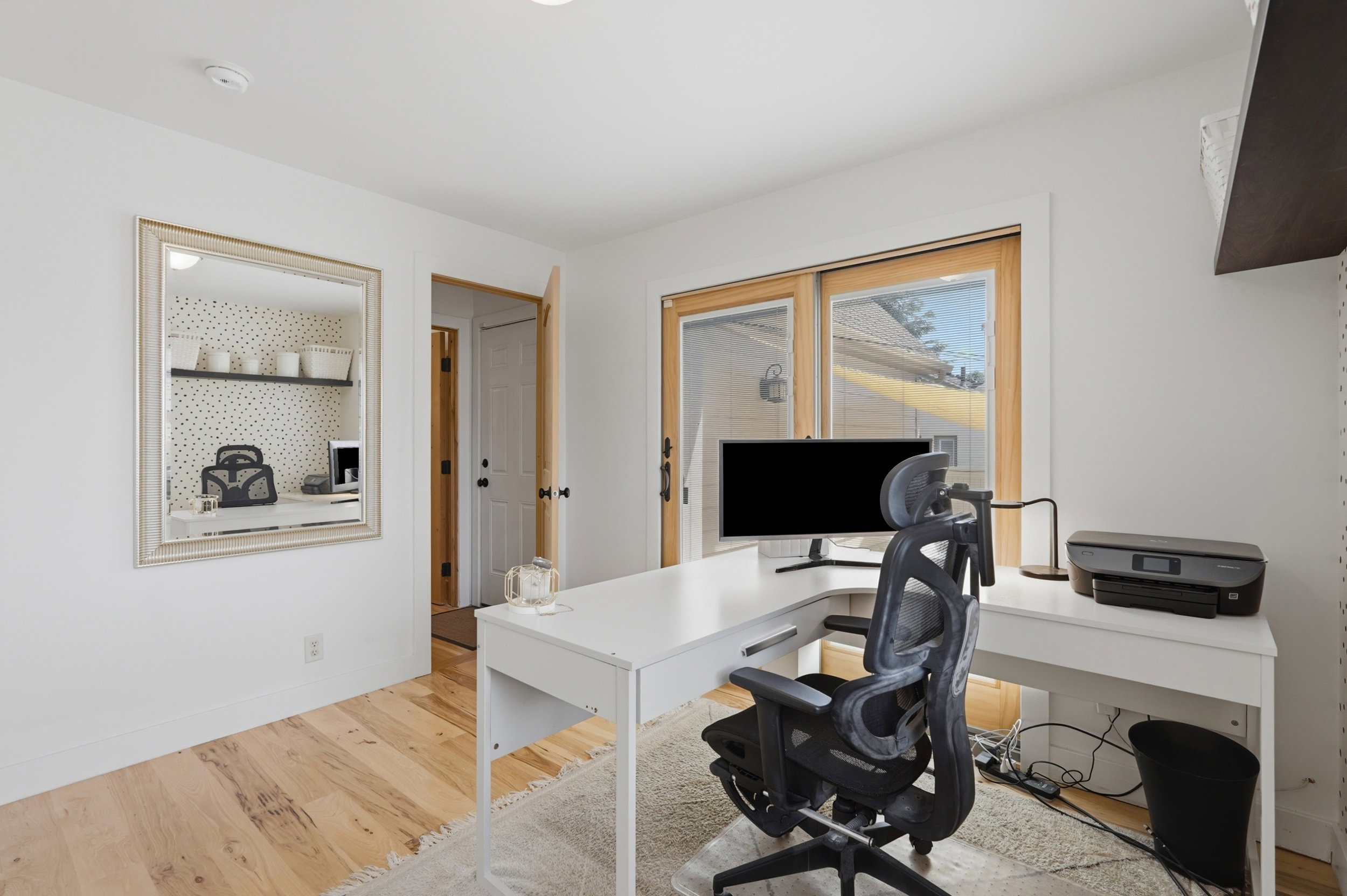 Bright room featuring wood-finish flooring, white walls, and a sliding glass door with wood trim