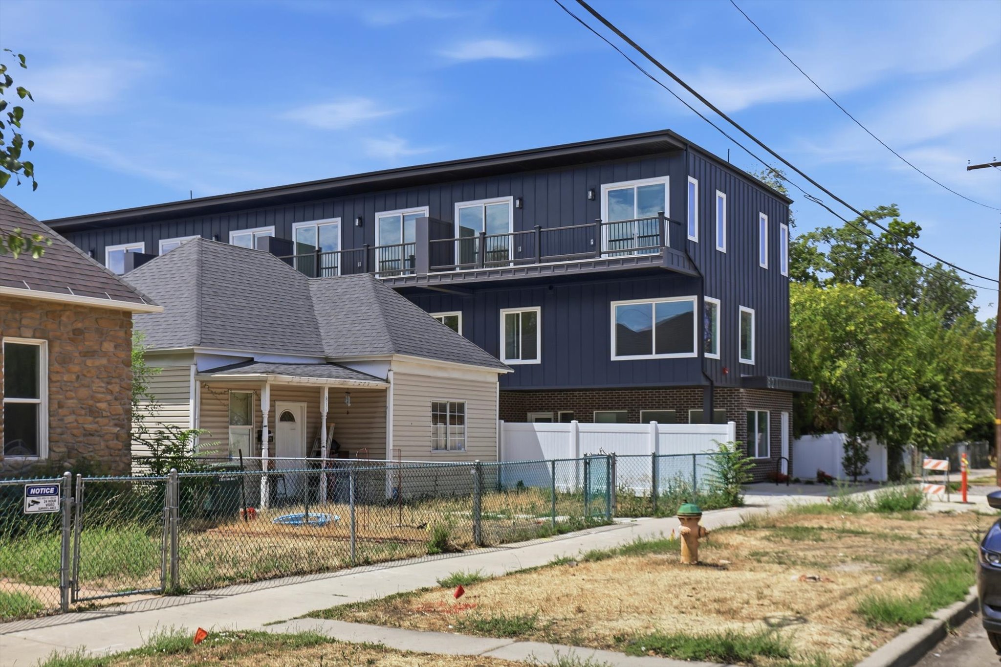 Modern multi-story building featuring dark vertical siding and a brick base