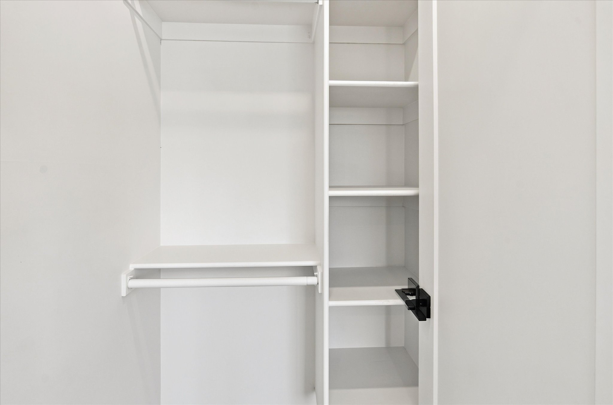Built-in closet system featuring white shelving and a hanging rod
