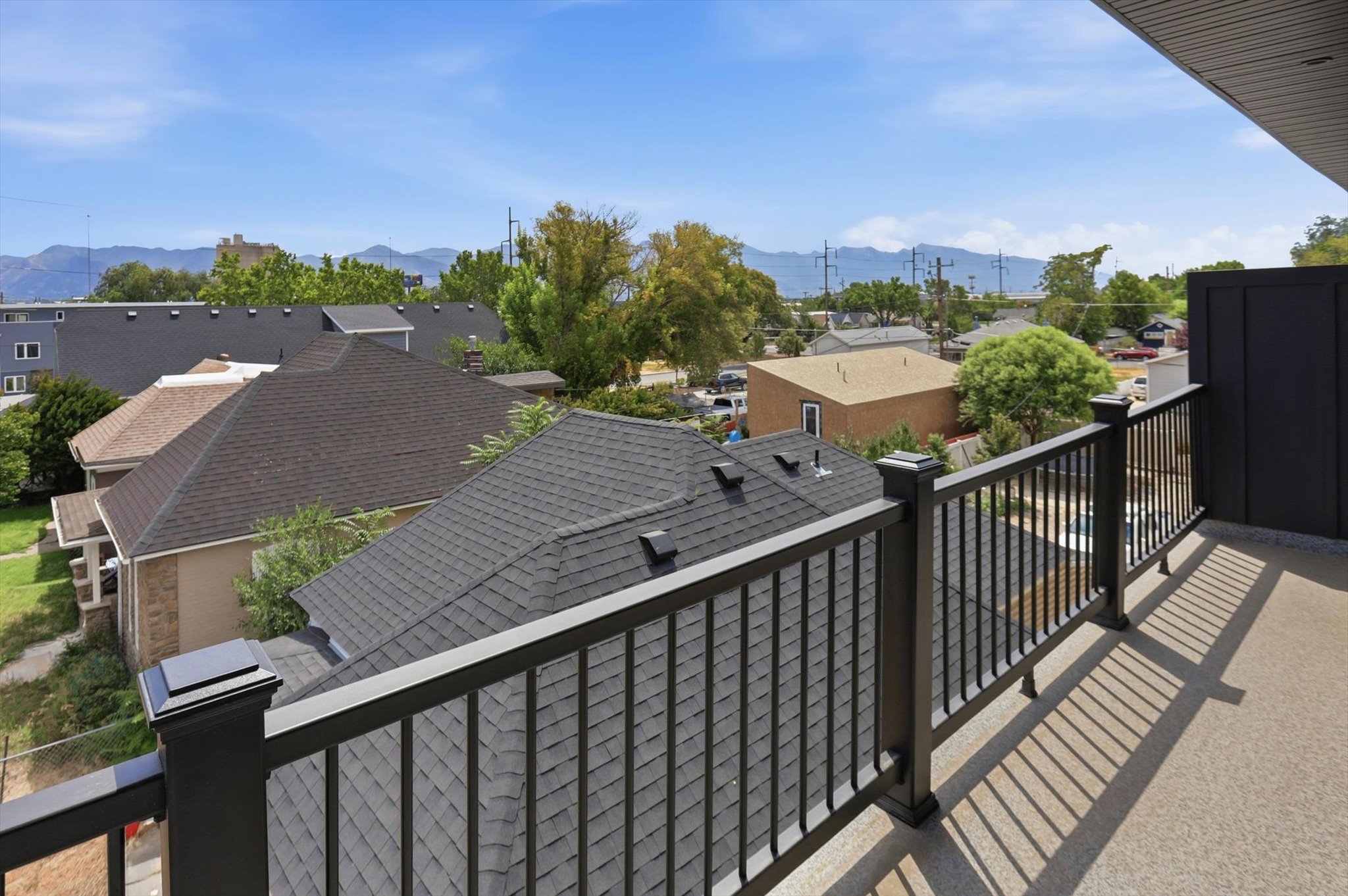 Rooftop deck featuring a durable railing system, privacy wall, and expansive neighborhood setting with distant mountains