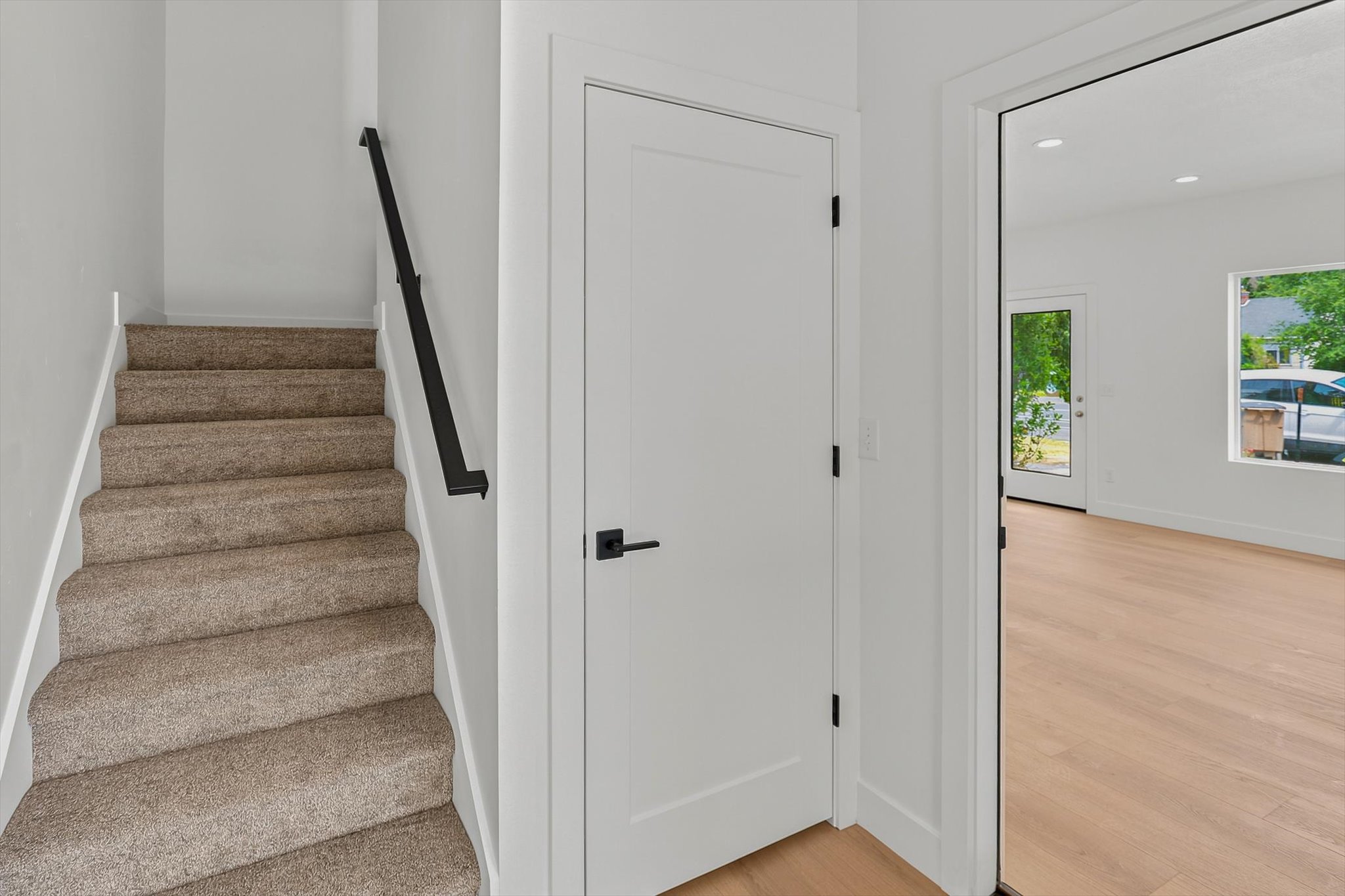 Carpeted staircase featuring a black handrail and white risers