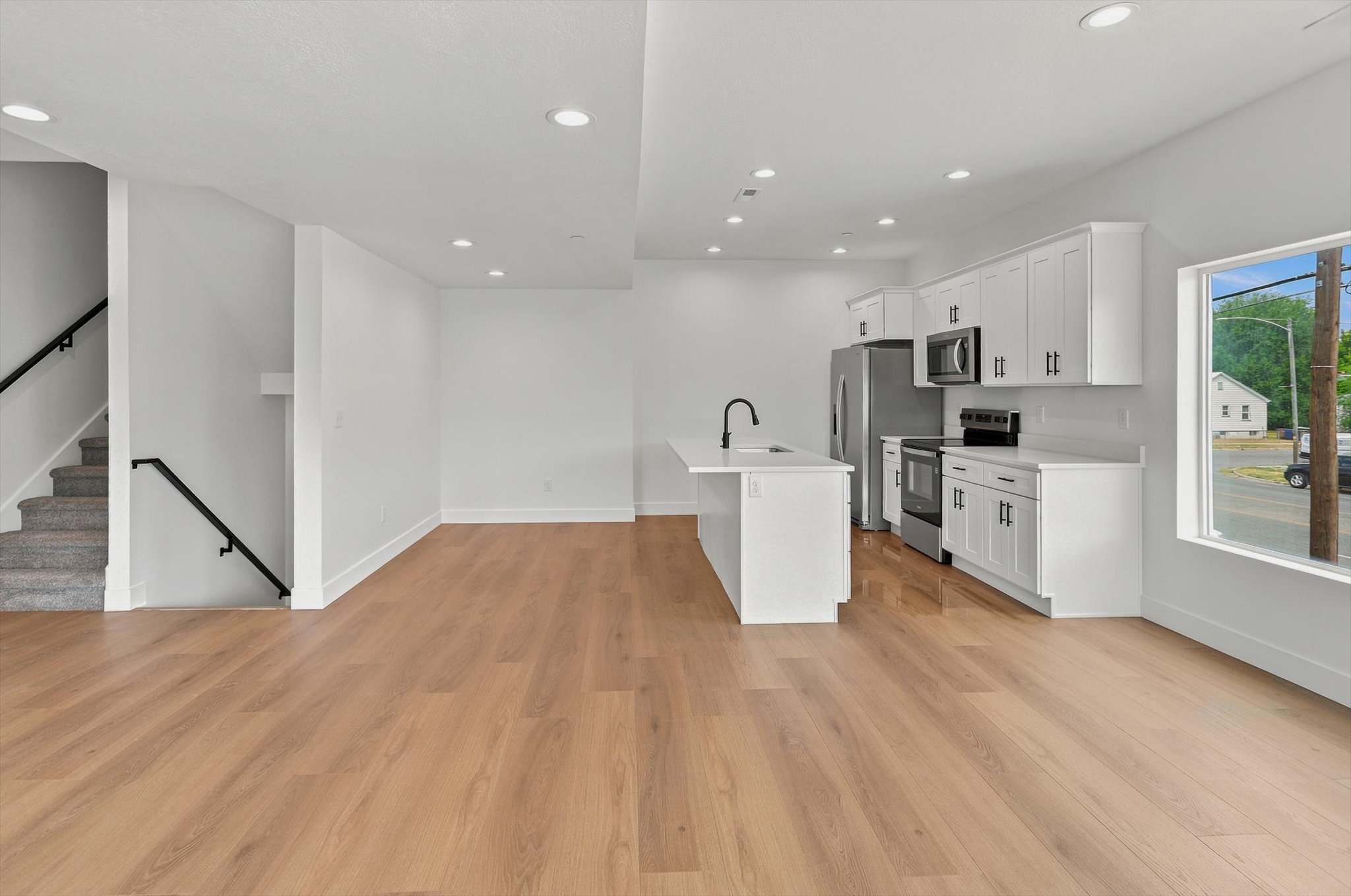 Open-concept living area featuring wood-finish flooring, recessed lighting, and a modern kitchen