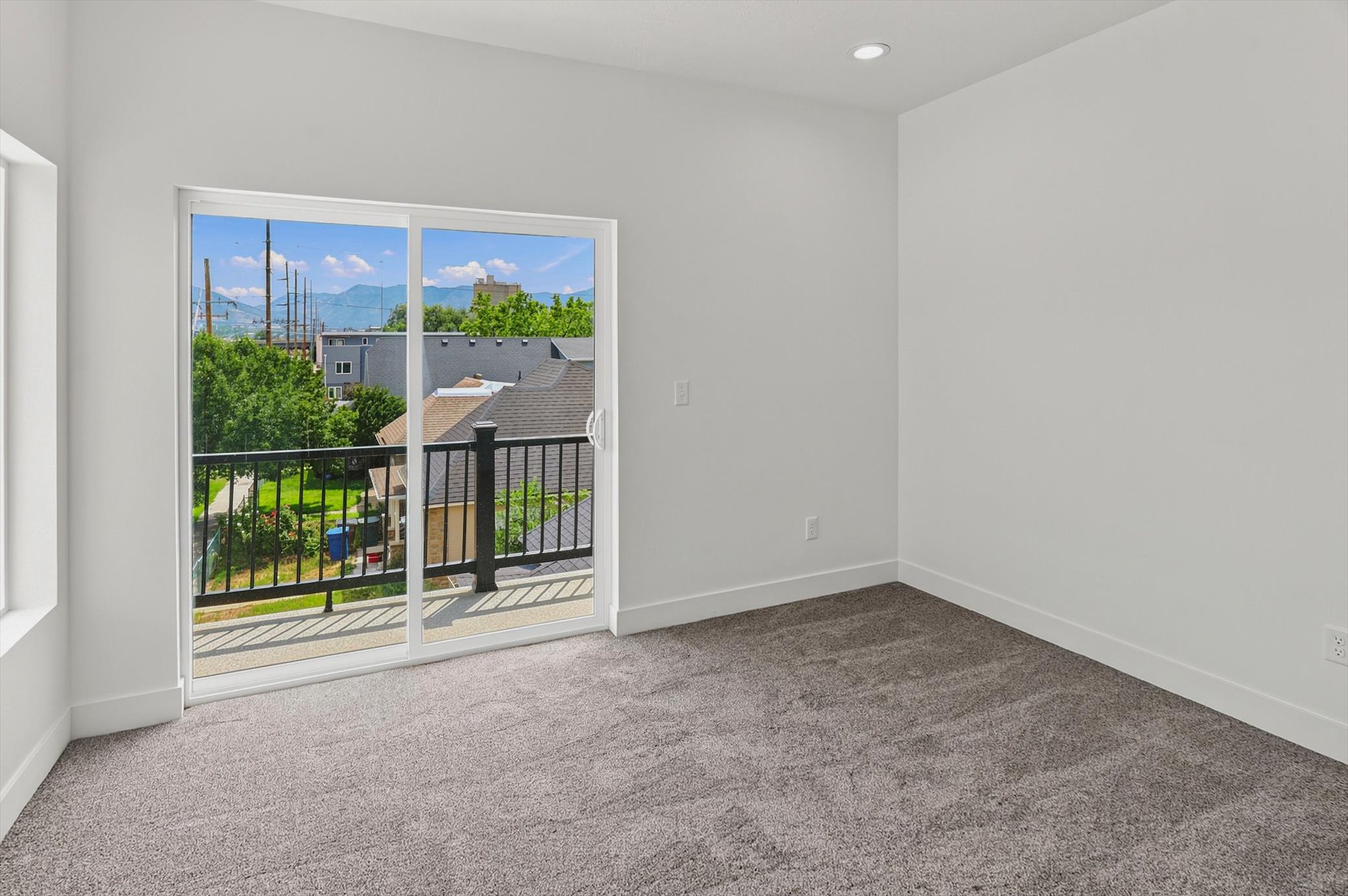 Spacious room featuring light gray carpet, crisp white walls, and a recessed ceiling light