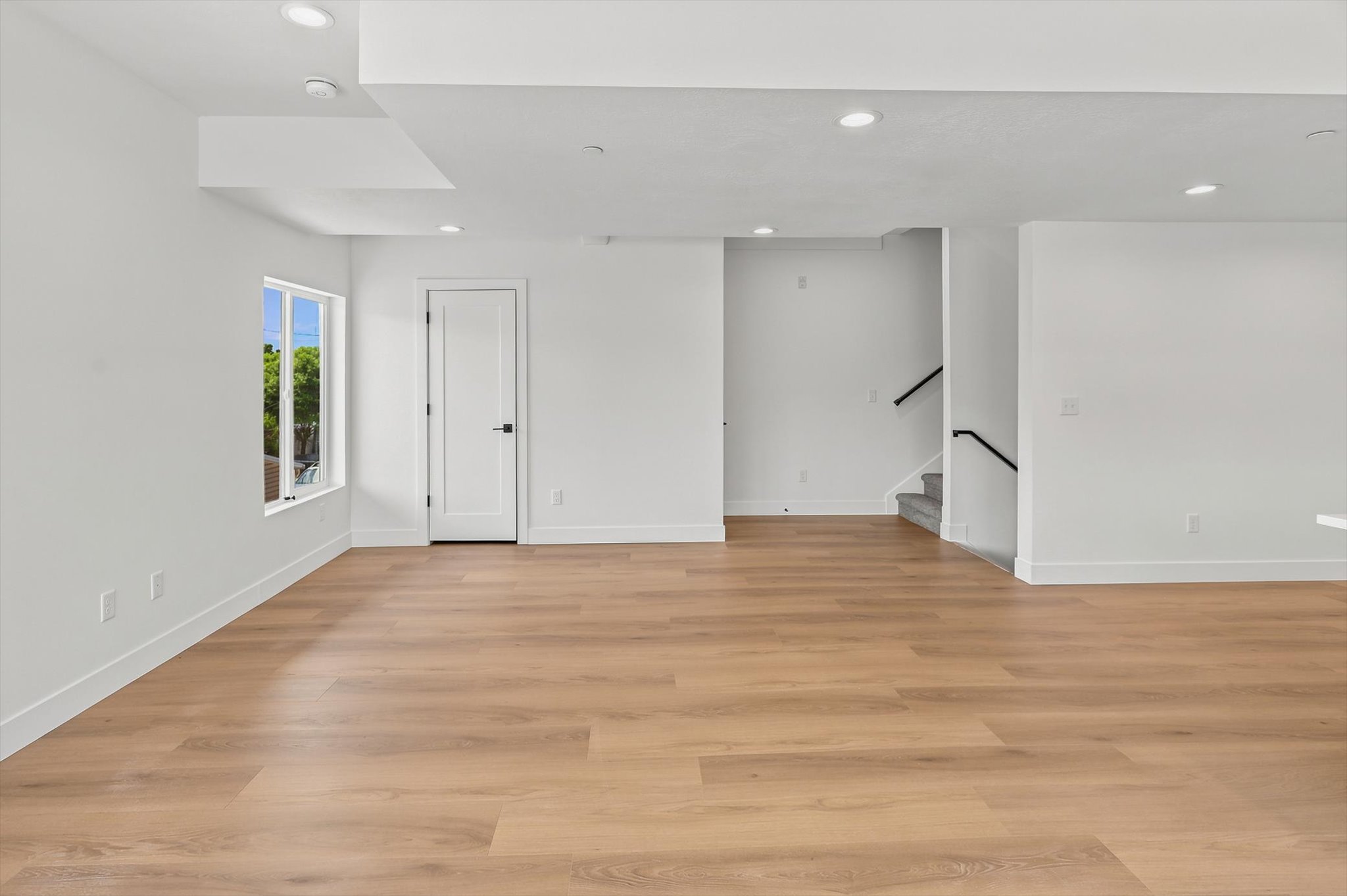 Open-concept living area with wood-finish flooring, recessed lighting, and white walls