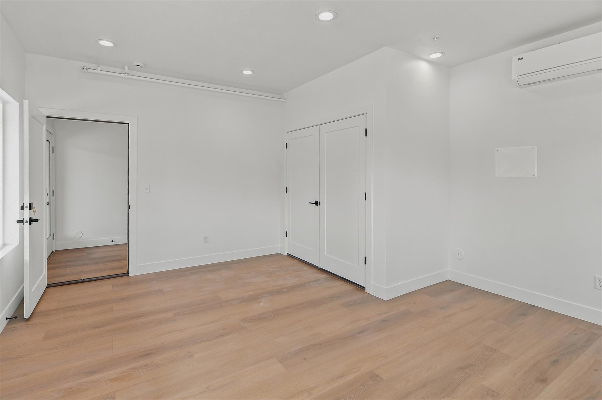 Spacious room featuring wood-finish flooring, recessed lighting, and a built-in air conditioning unit