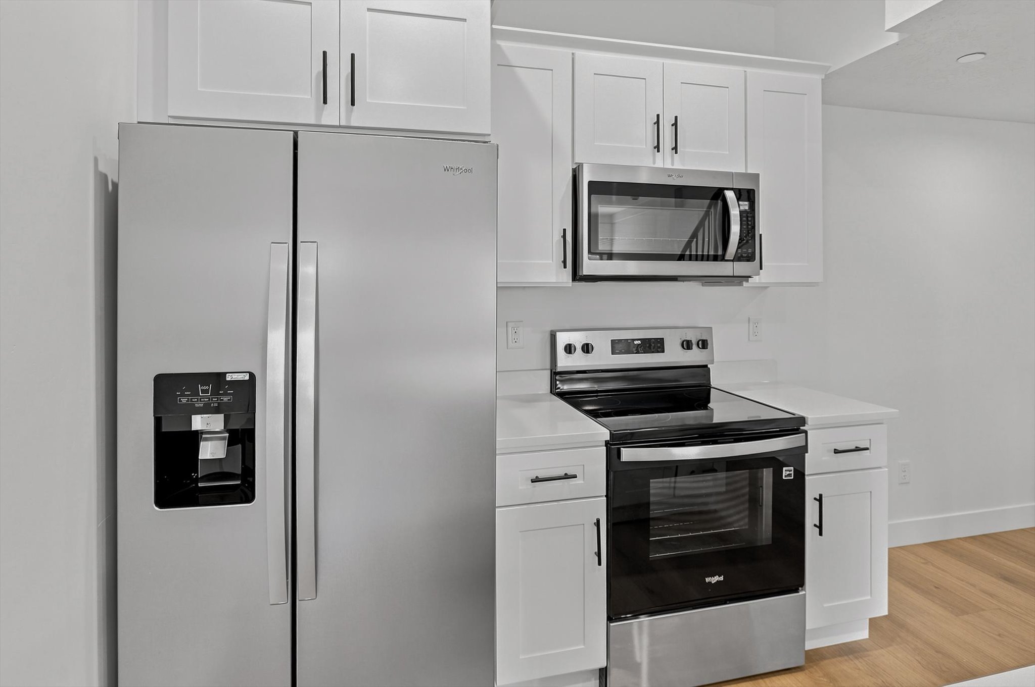 Modern kitchen appliances featuring a stainless steel side-by-side refrigerator, microwave, and electric range