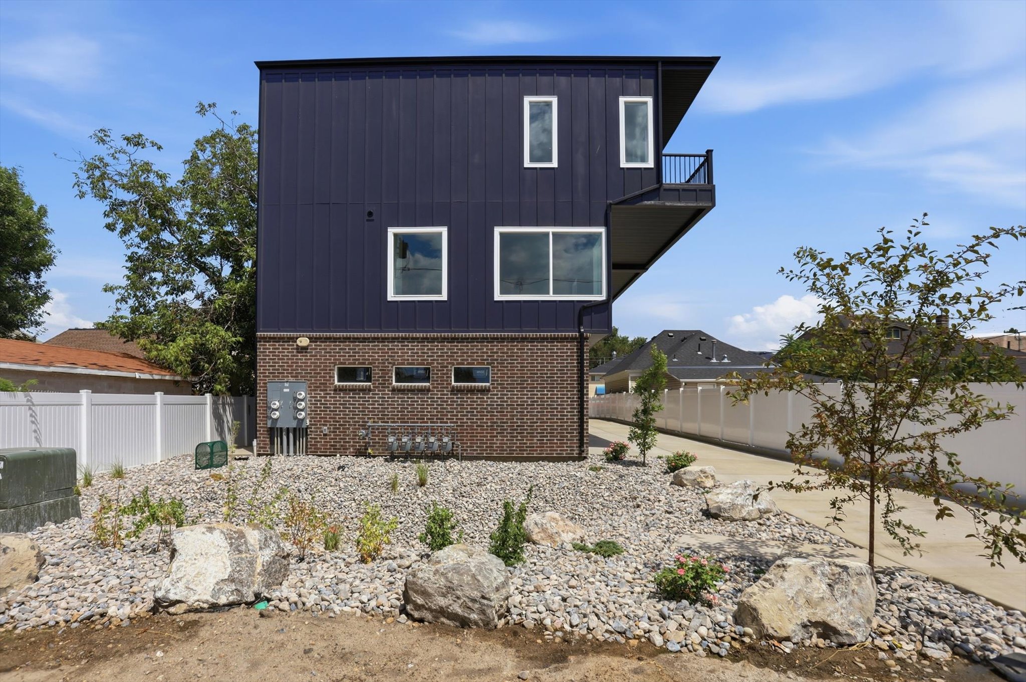 Modern multi-story exterior featuring dark vertical siding and a brick base