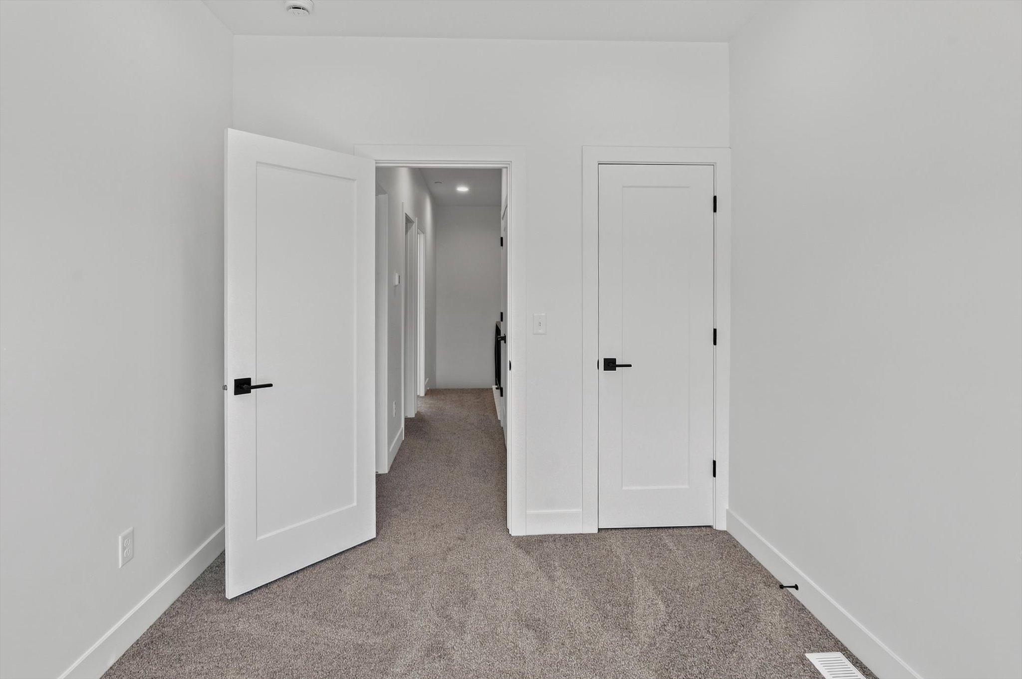 Interior room featuring white walls, gray carpet, white trim, and white doors with matte black hardware
