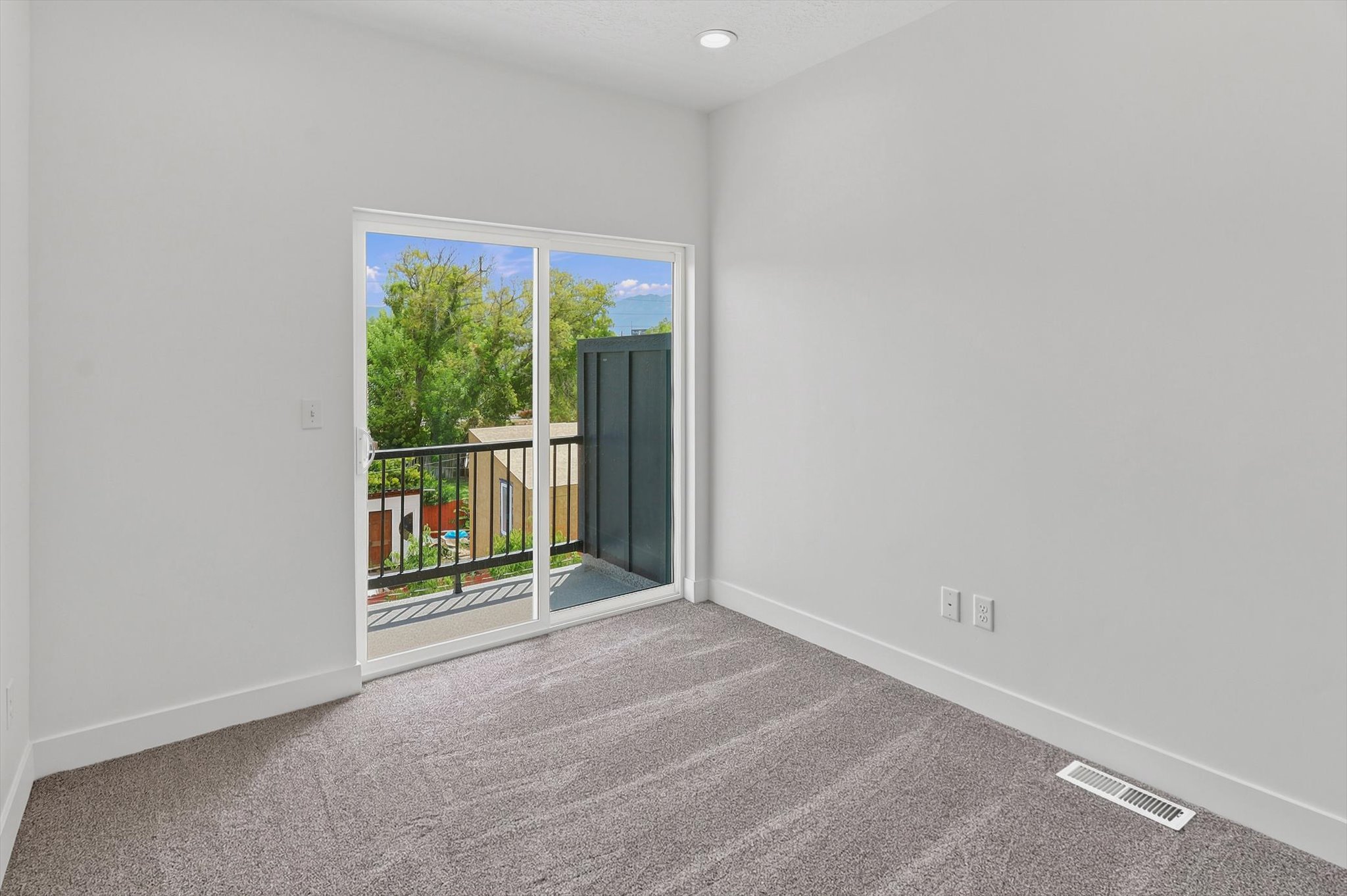 Room with light gray wall paint, gray carpet flooring, and white baseboards
