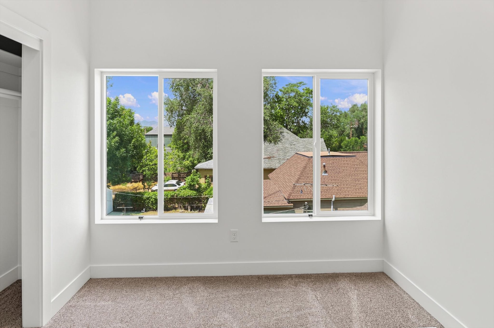 Room featuring two large windows, white trim, and a neutral carpet