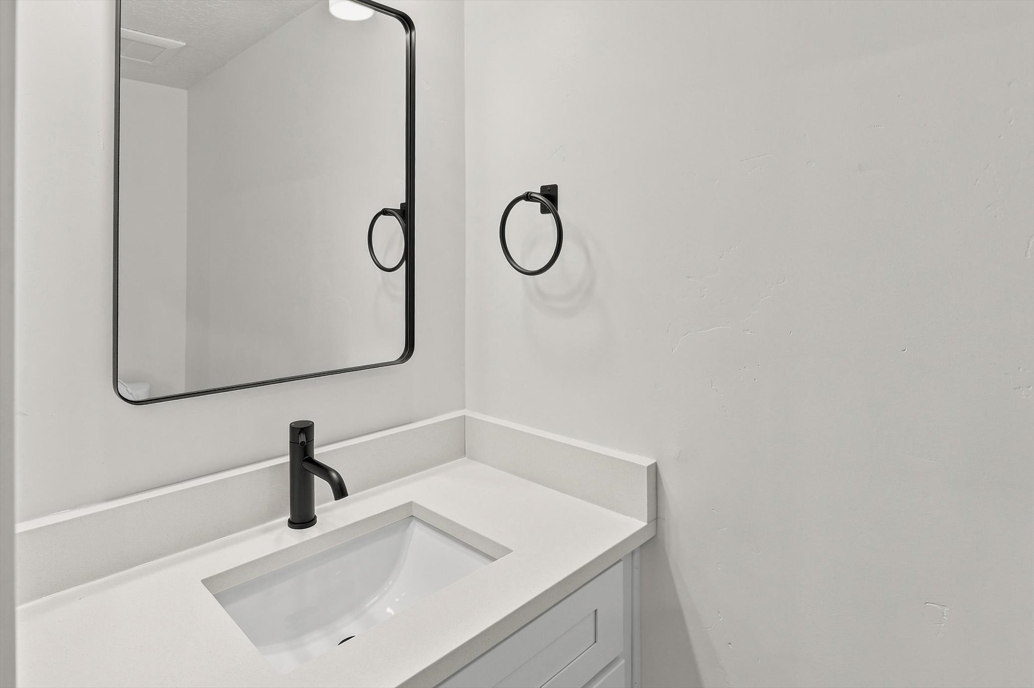 Bathroom vanity featuring a matte black faucet, an integrated sink, and a light-toned countertop