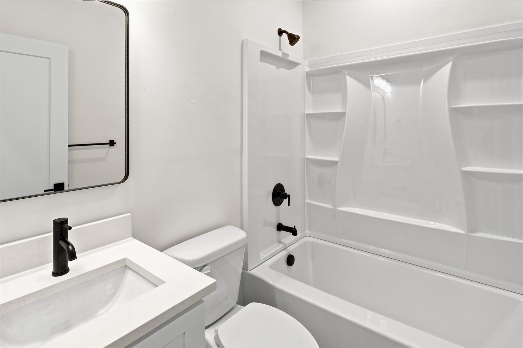 Bathroom featuring a white vanity with an integrated sink, matte black faucet, and a contemporary frameless mirror