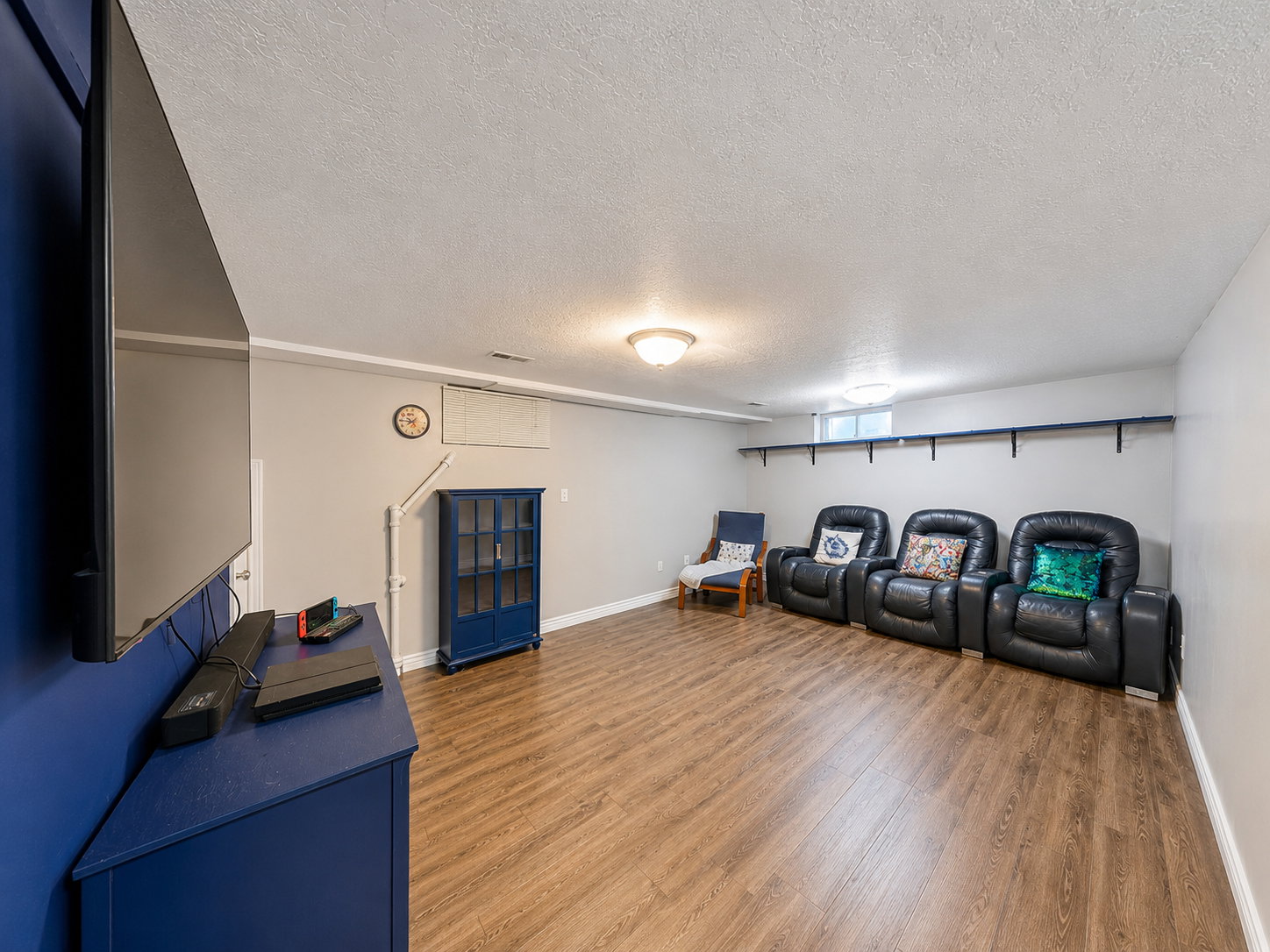 Spacious recreation room featuring wood-finish flooring, light gray walls, and white trim