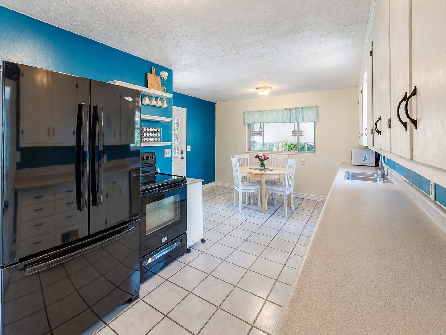 Kitchen featuring white tile flooring, white cabinetry, and a light-colored countertop