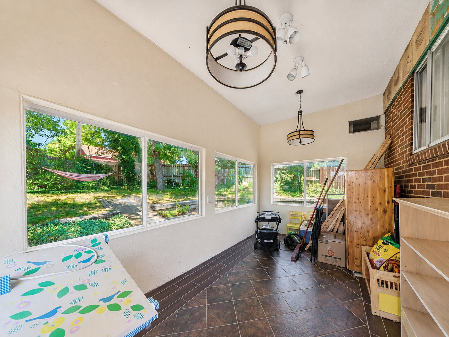 Sunroom with high ceilings, large windows, recessed lighting, two decorative light fixtures, and tiled flooring