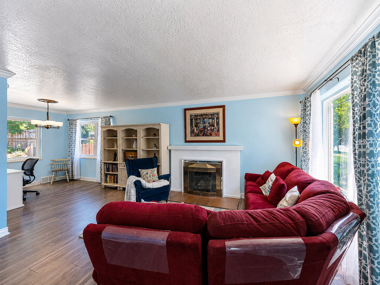 Living space featuring wood-finish flooring, a fireplace with a white mantel, and an adjacent built-in shelving unit