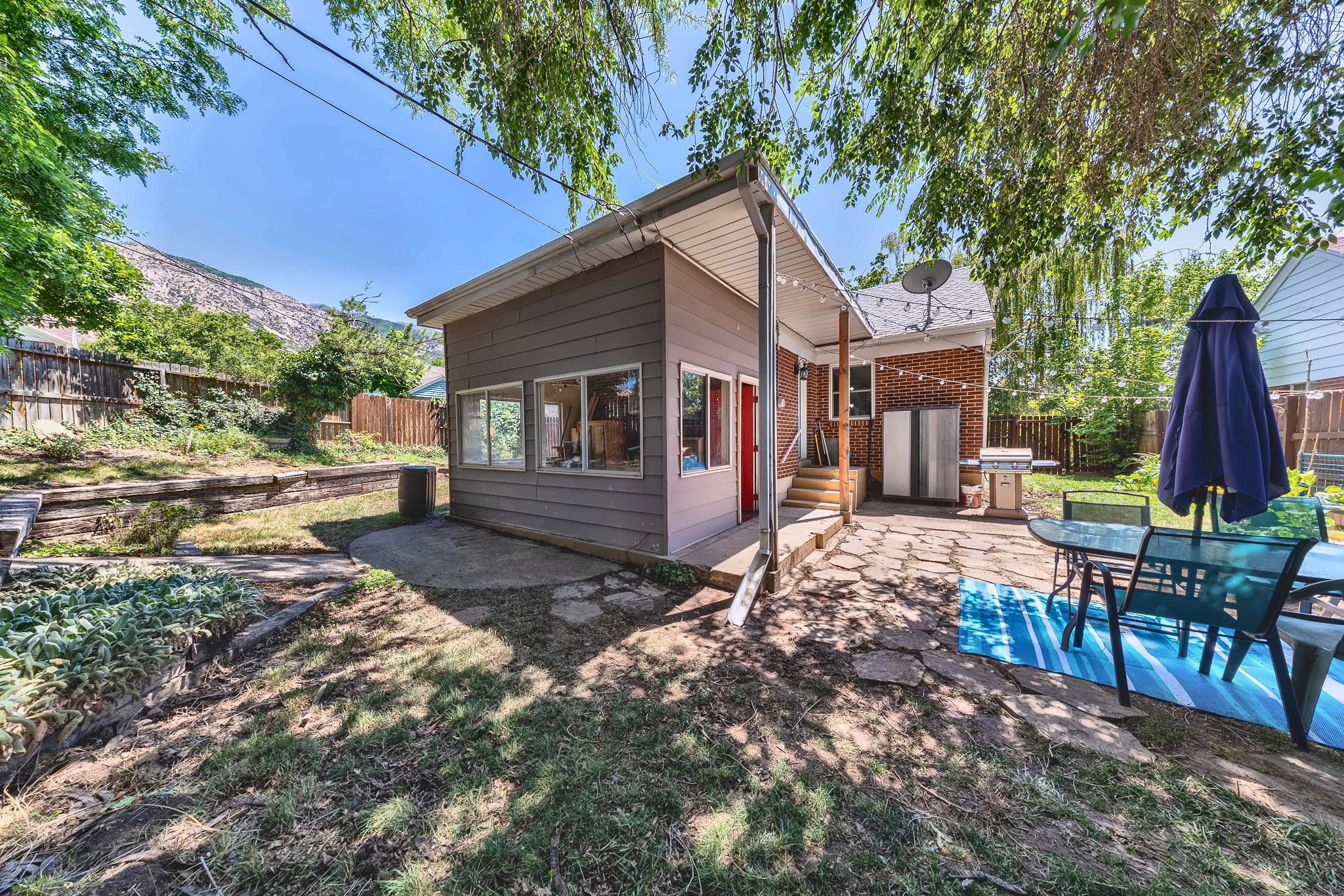 Exterior living space featuring a stone patio and an additional structure with multiple windows