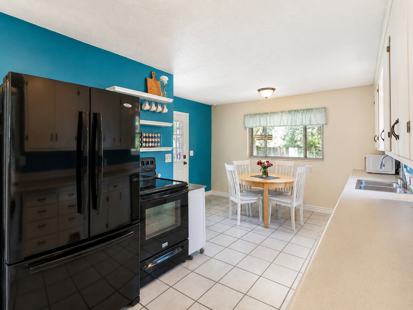 Kitchen featuring black appliances, white cabinetry, light countertops, and tile flooring