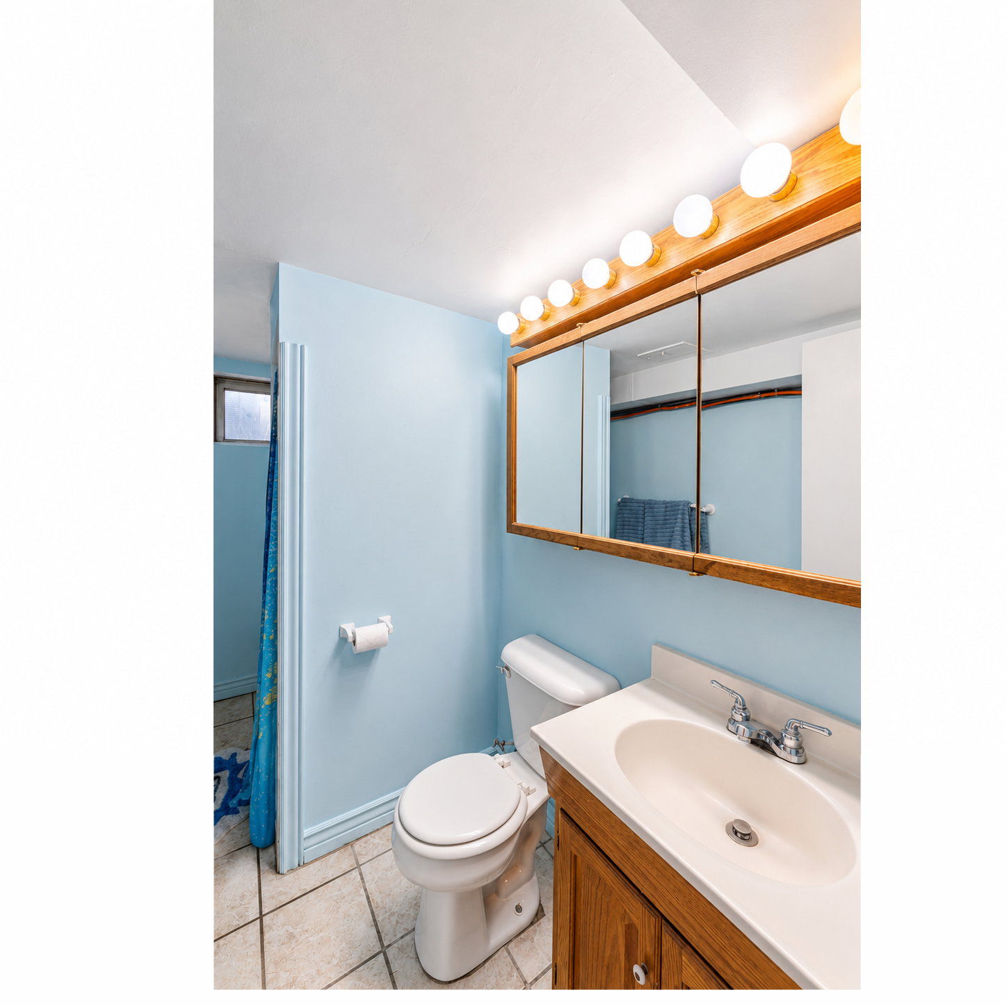 Bathroom featuring a wood-finish vanity with an integrated sink, a coordinating wood-framed mirrored medicine cabinet, and a five-bulb vanity light fixture
